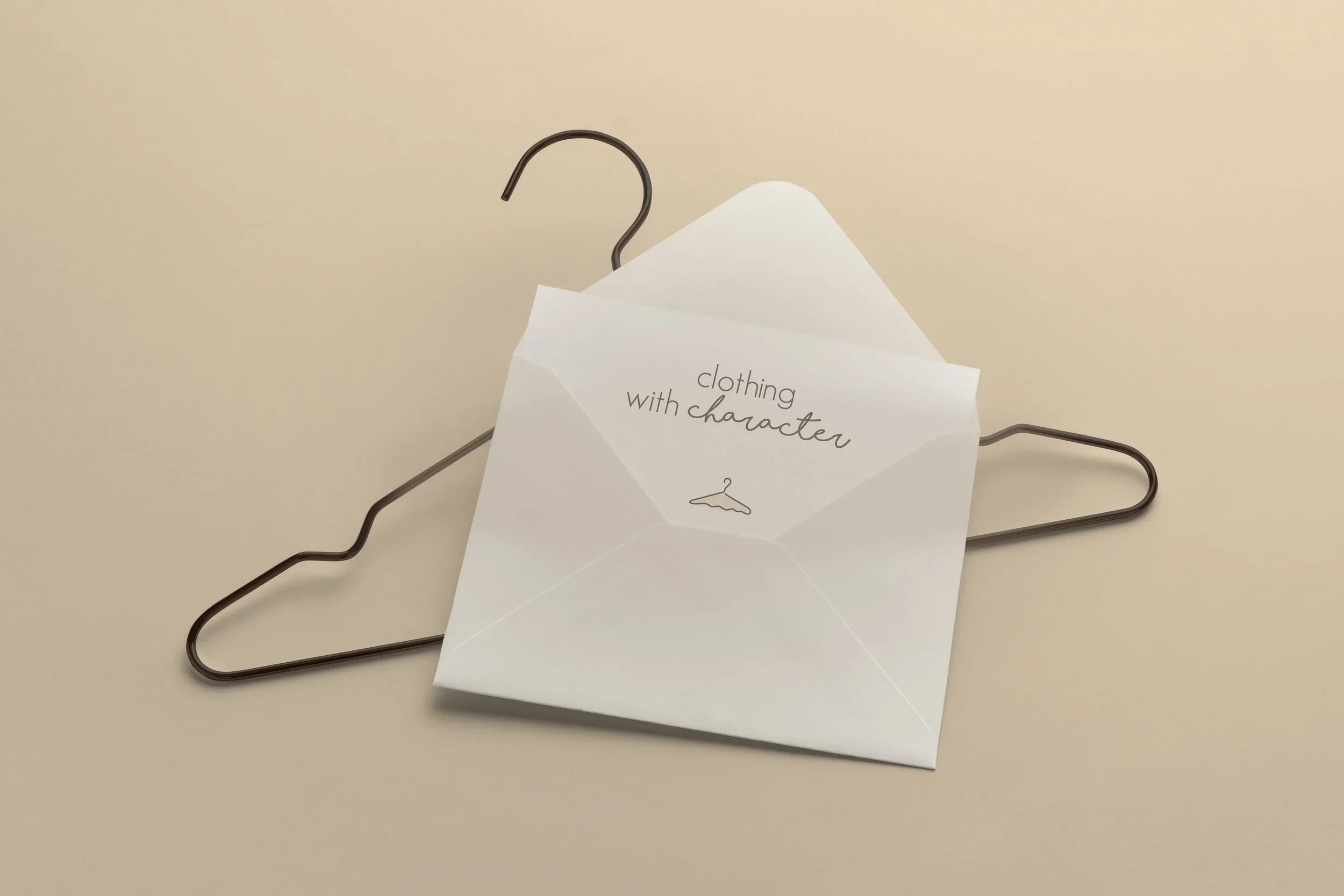 A white greeting card with the text 'clothing with character' from PALAZZO Domburg and a small illustration of a hanger, resting on a dark metal clothes hanger. BigStoryShort client.