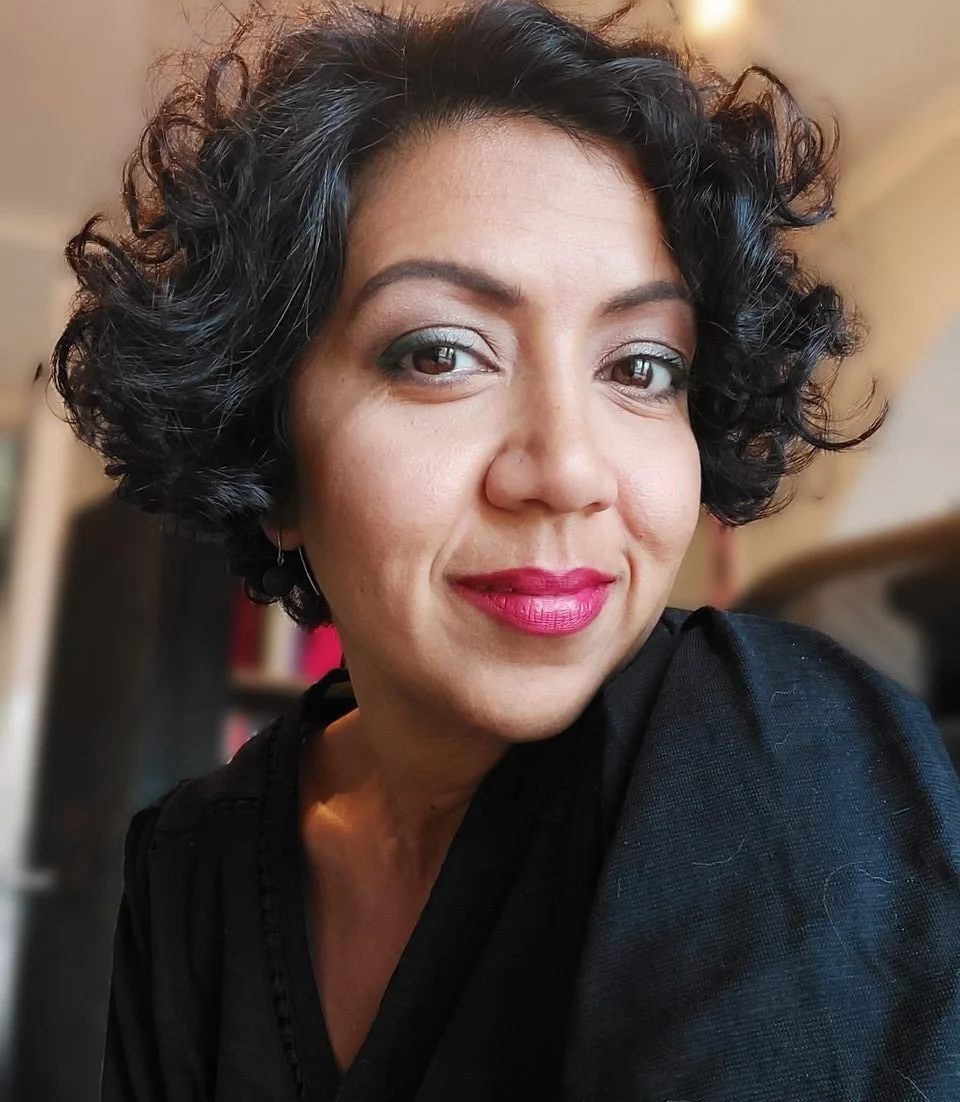 Sabrina Ahmed, Burnout & Resilience Coach smiling at the camera in her office.