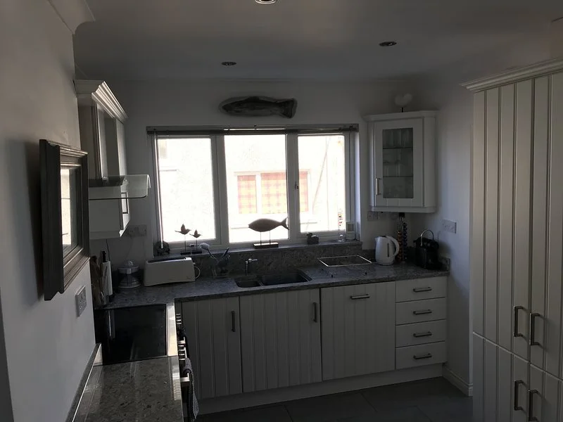 Kitchen with a window, white cabinets, and various appliances including a kettle and toaster.