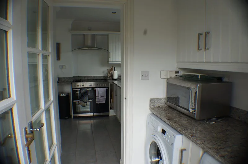 Kitchen with stove, microwave, washing machine, and white cabinets.