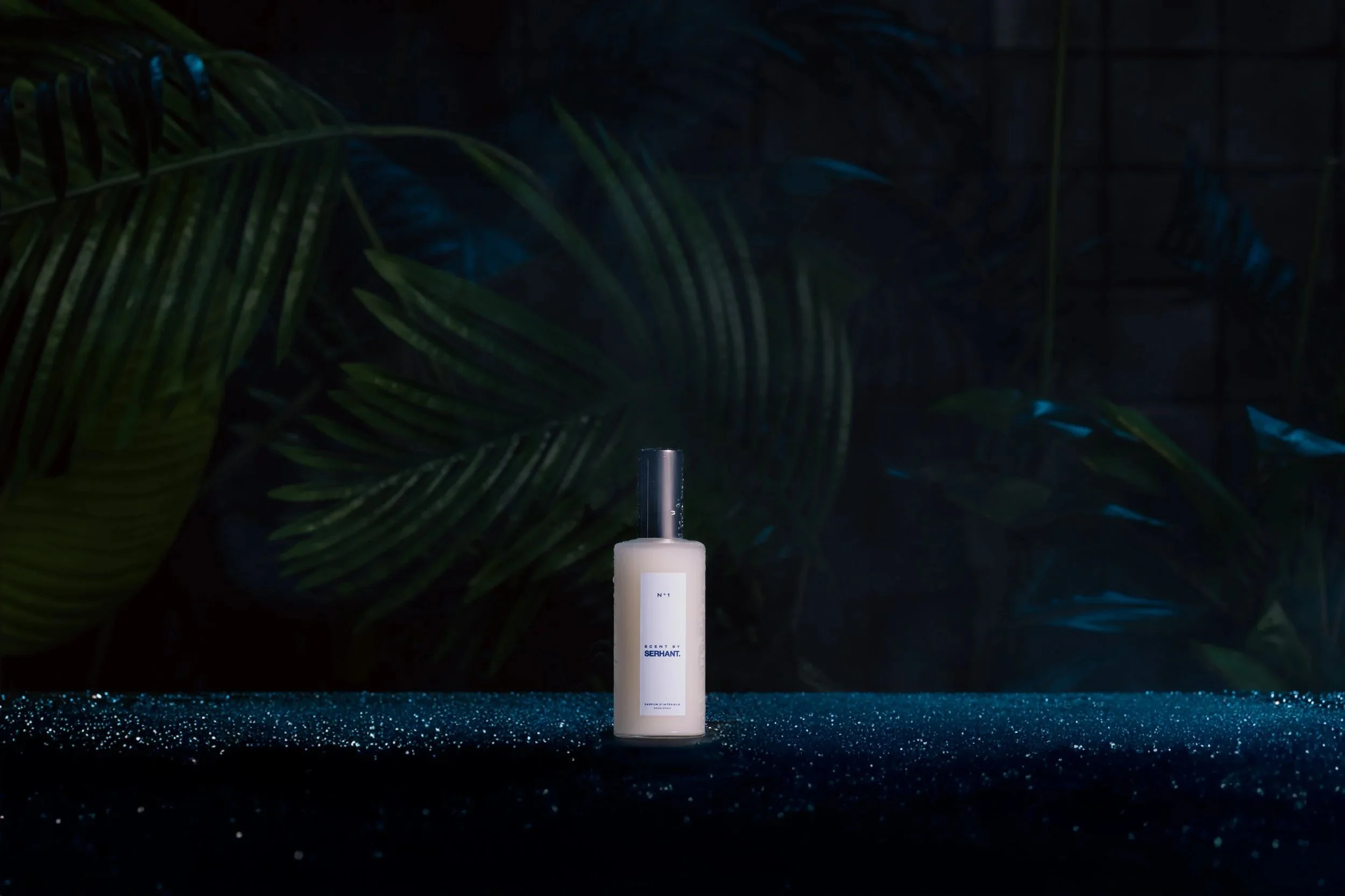 Scent by SERHANT home atmosphere spray — white bottle with black top, styled on a dark glittery surface