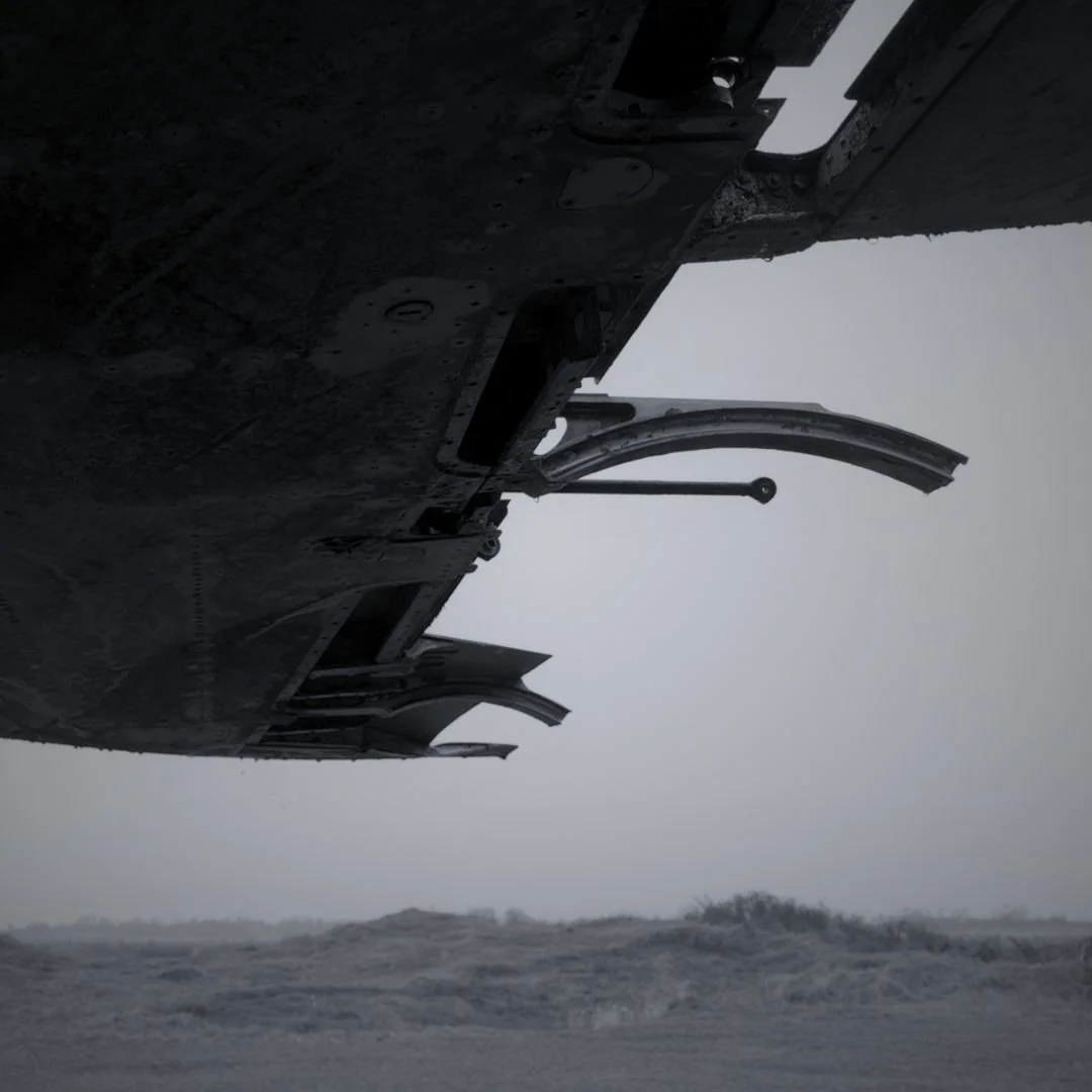View from underneath a military aircraft flying over rough ocean waters in stormy weather.