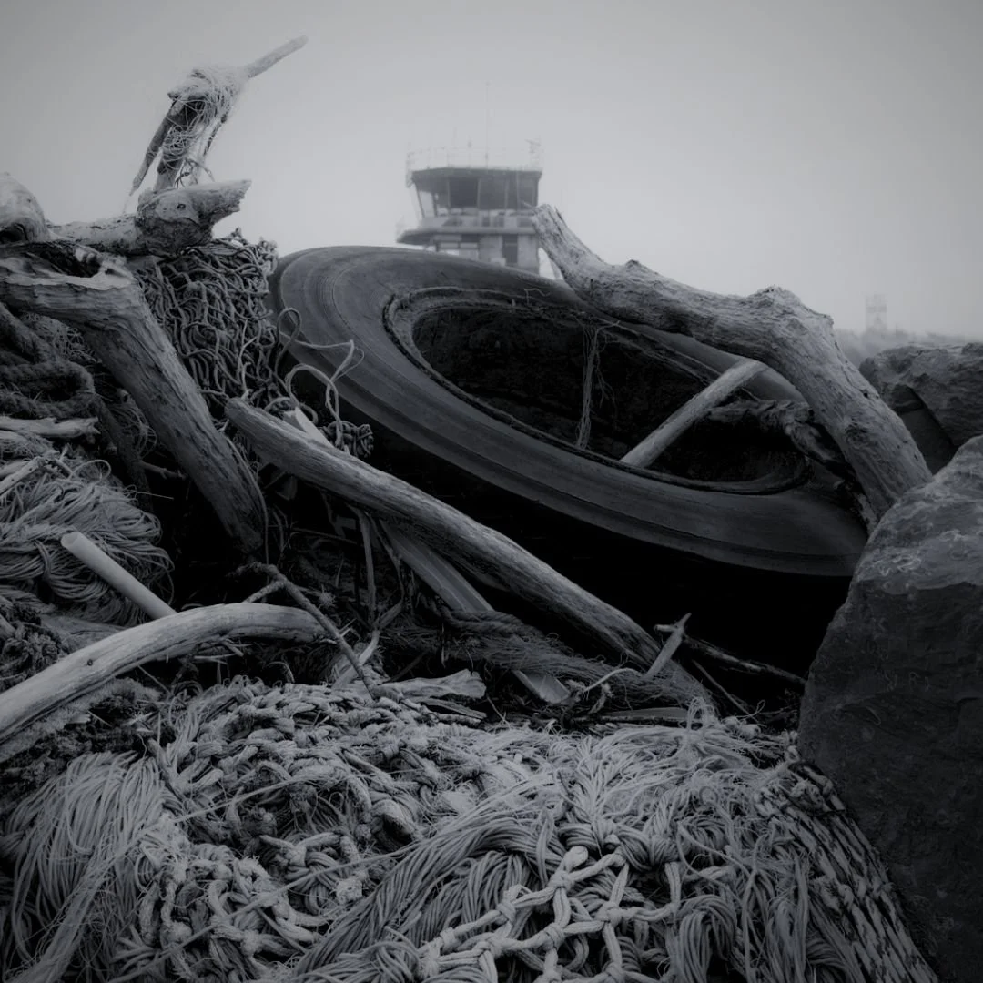 A monochrome photo of a wrecked airplane with twisted metal and debris, with a control tower in the background.