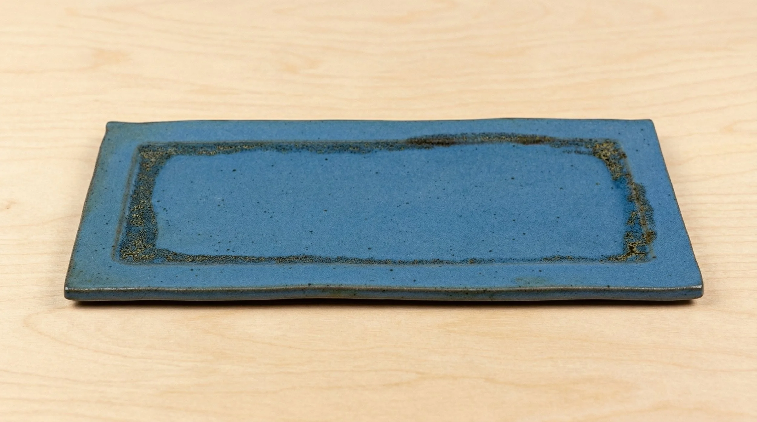 A rectangular blue ceramic platter, placed on a light wood surface.