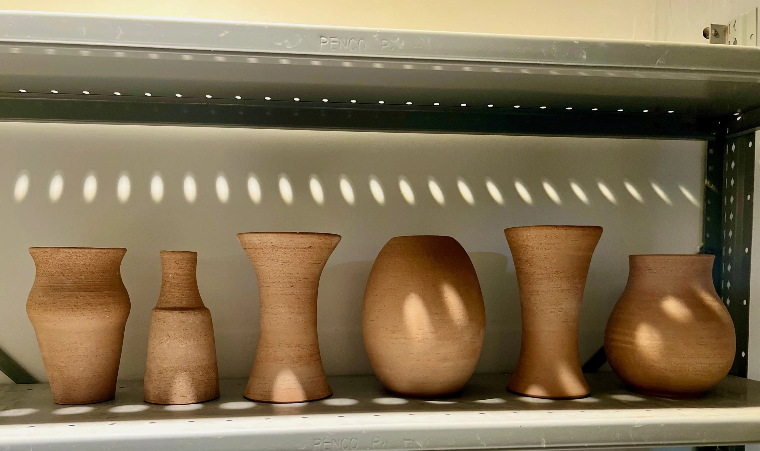 Six dark stoneware vases of varying shapes and sizes, in greenware state prior to firing.