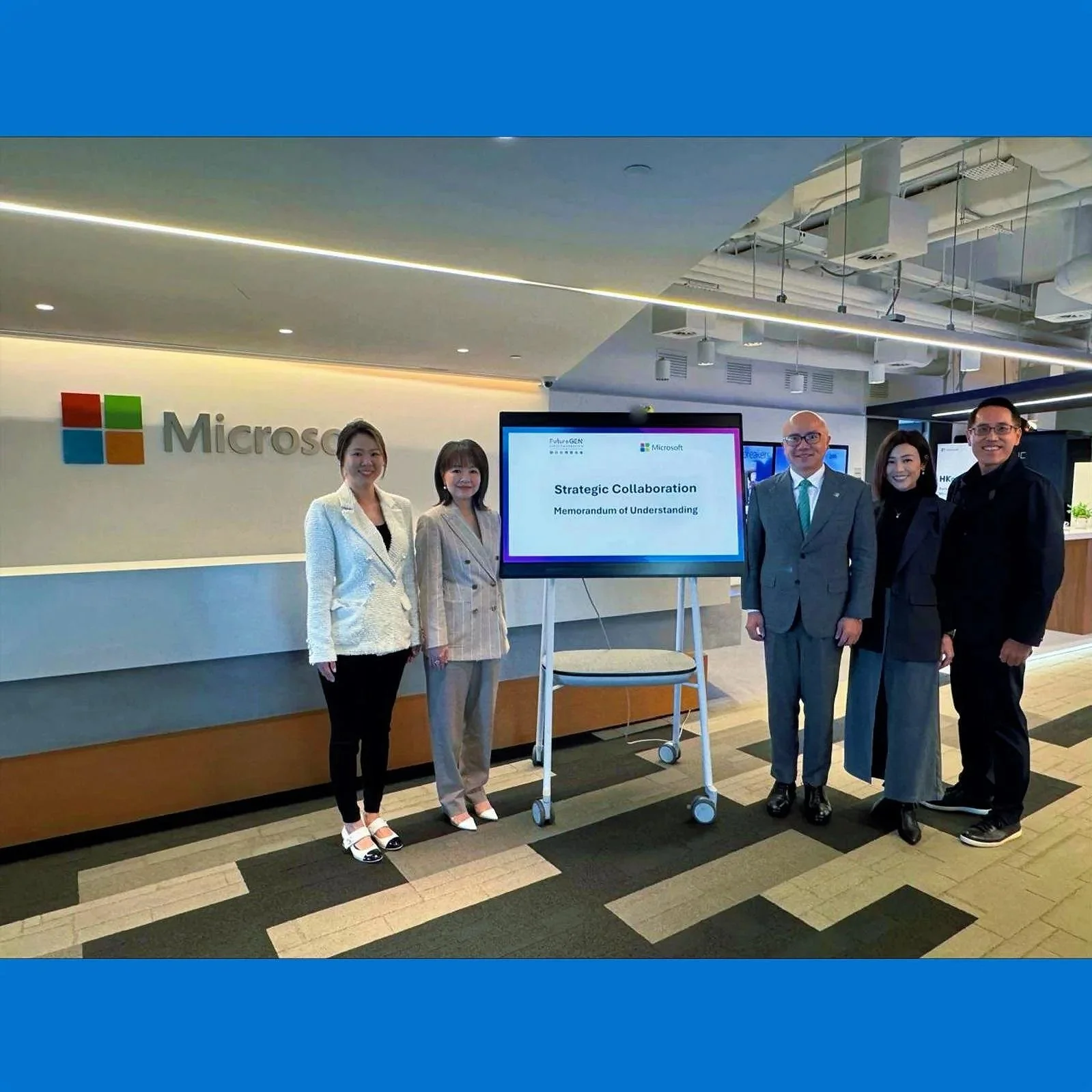 Professionals standing in Microsoft office lobby with a display screen showing 'Strategic Collaboration Memorandum of Understanding.'