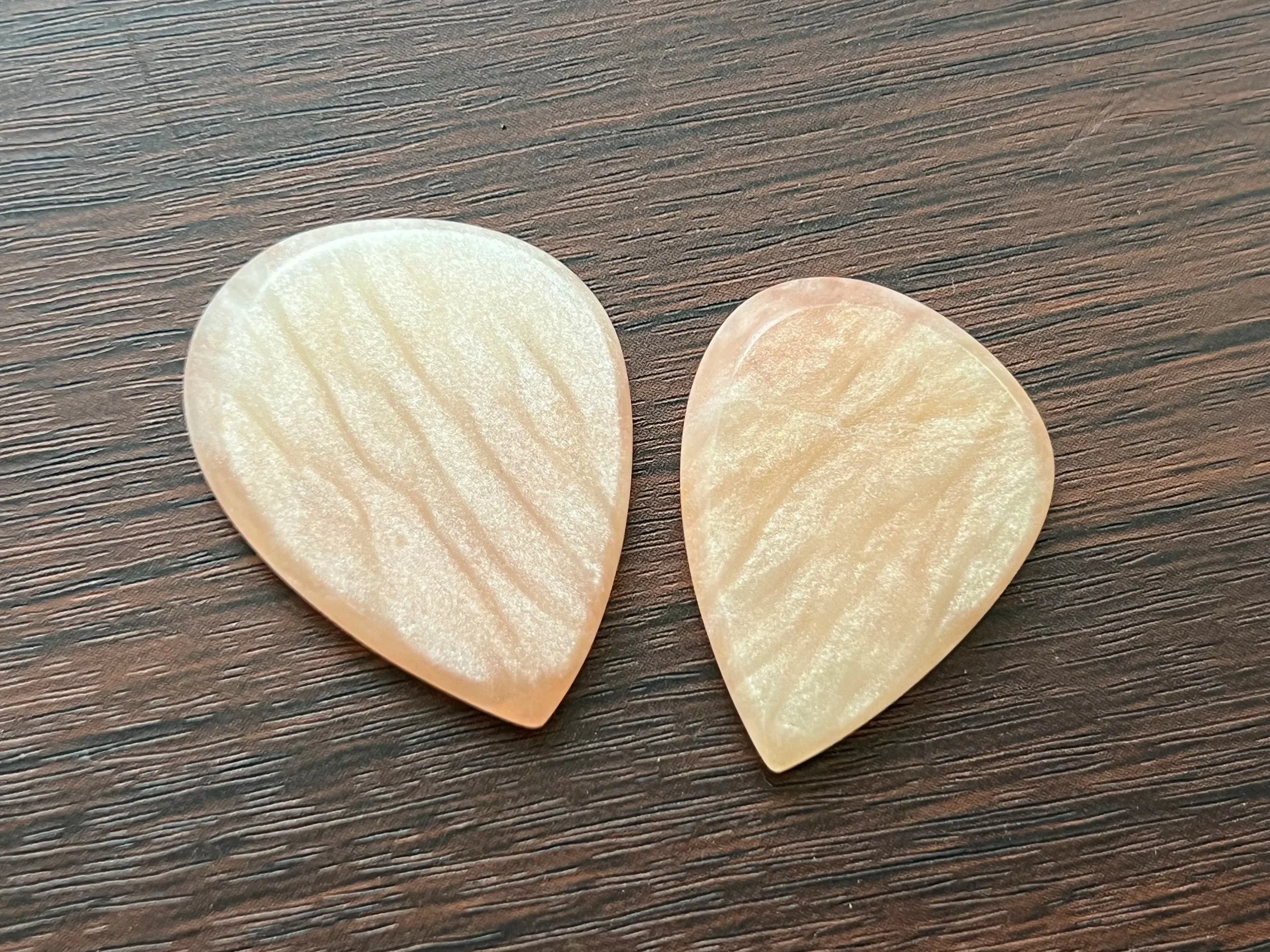 Close-up of two guitar picks on a wooden surface.
