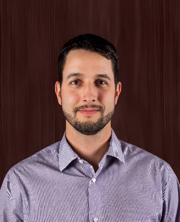 Brad Tymchyshyn, Vice President, Operations V2CM, standing in front of a wooden background.