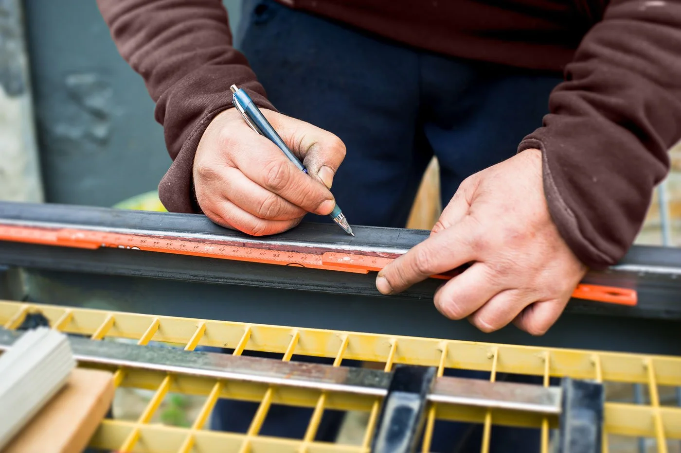 Person measuring a snowboard with a ruler and marking it with a pen.