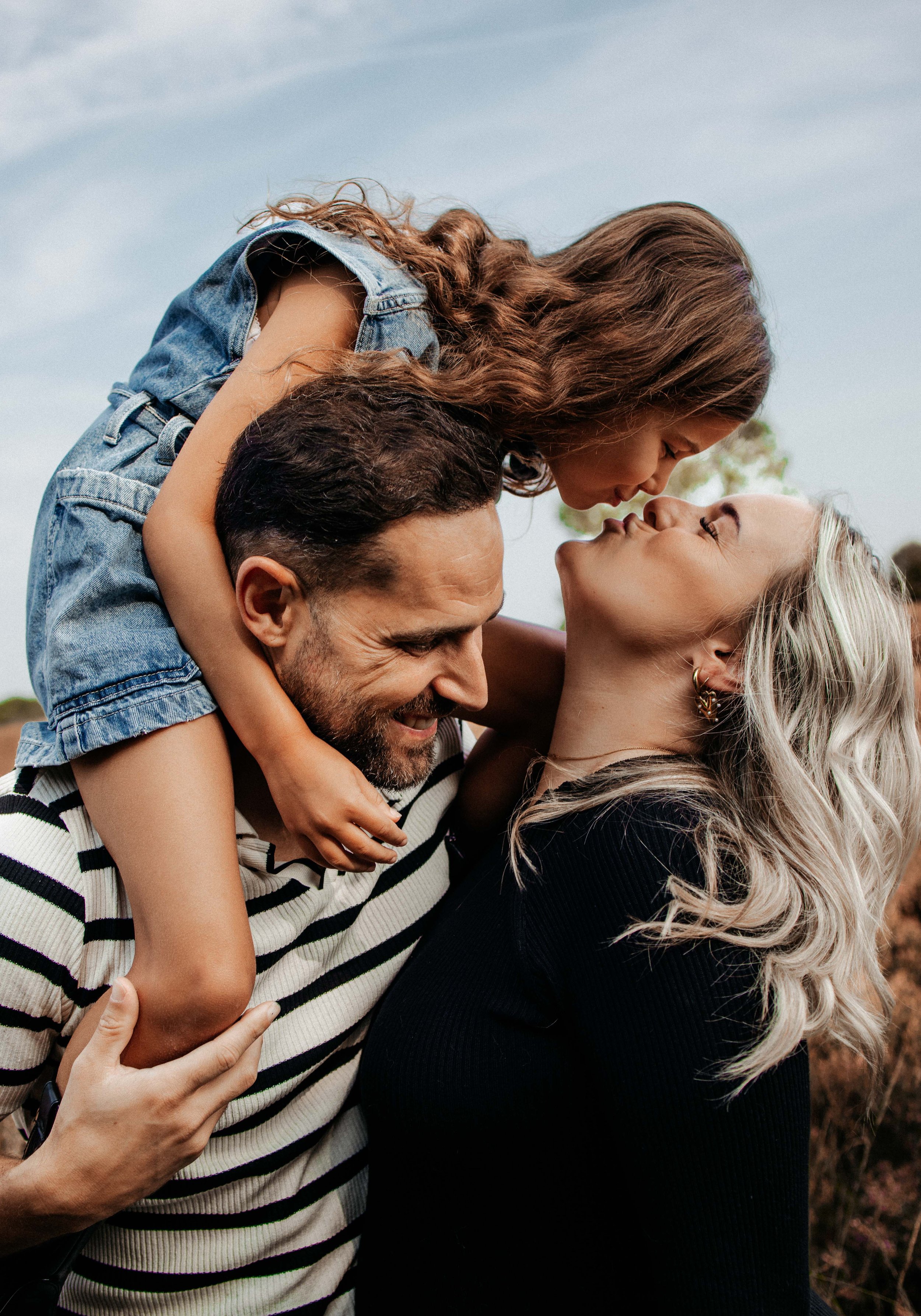 Foto van een gezin van drie met de dochter op de nek van haar vader