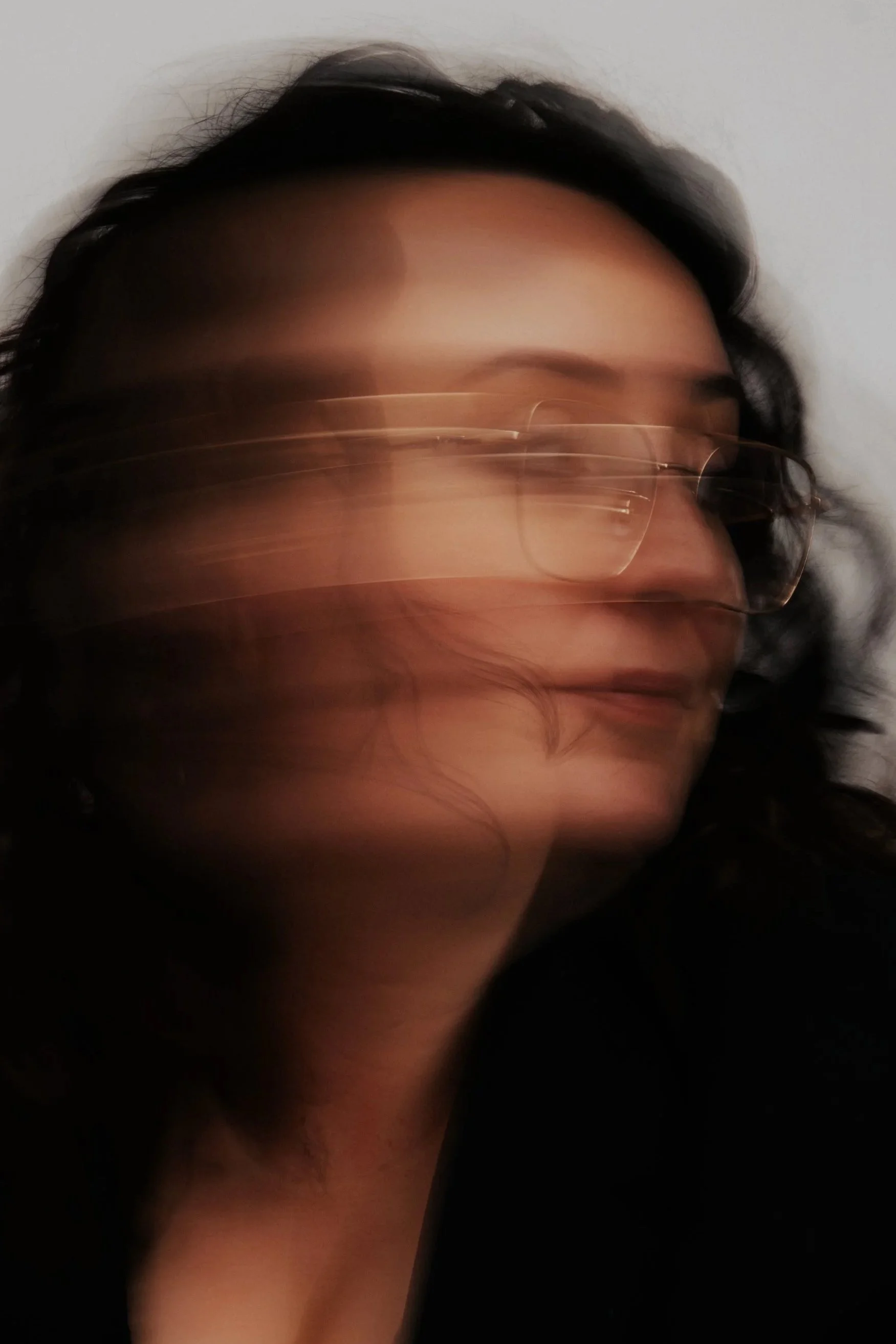 Portret van een persoon met donkere haar en brillen, wazig door beweging