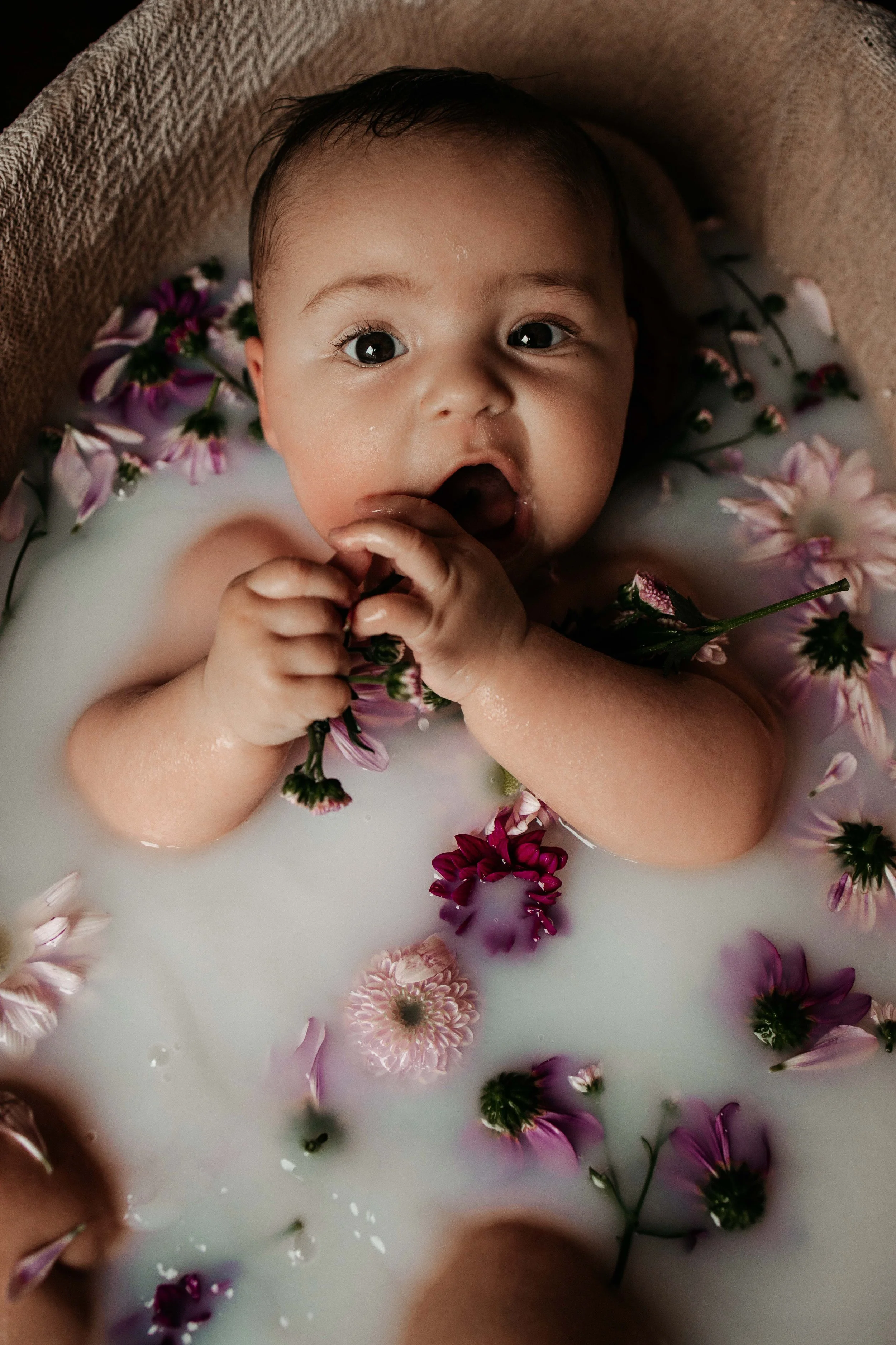 Foto van baby in melkbad met bloemen