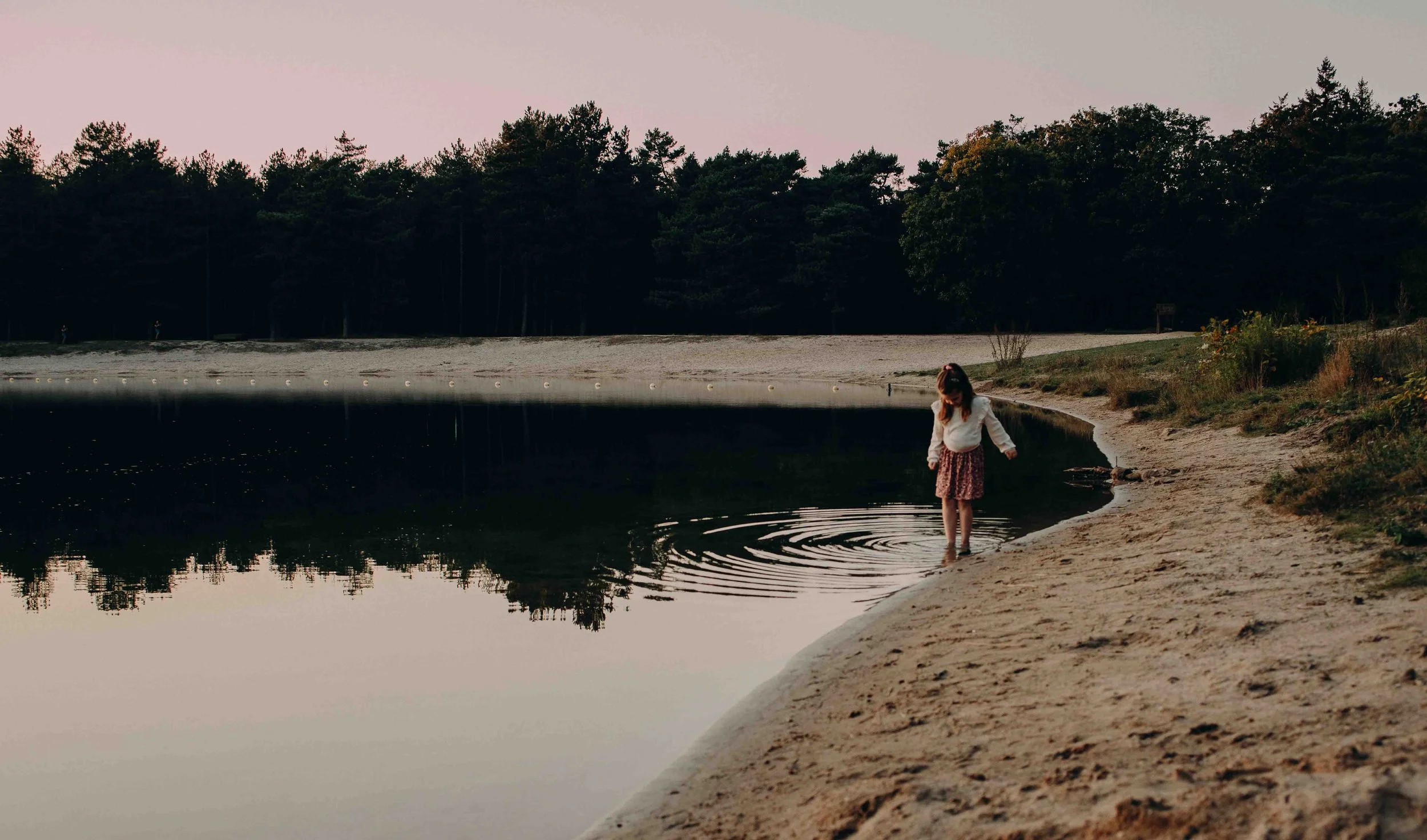 Foto van een klein meisje in de zomer bij een meertje