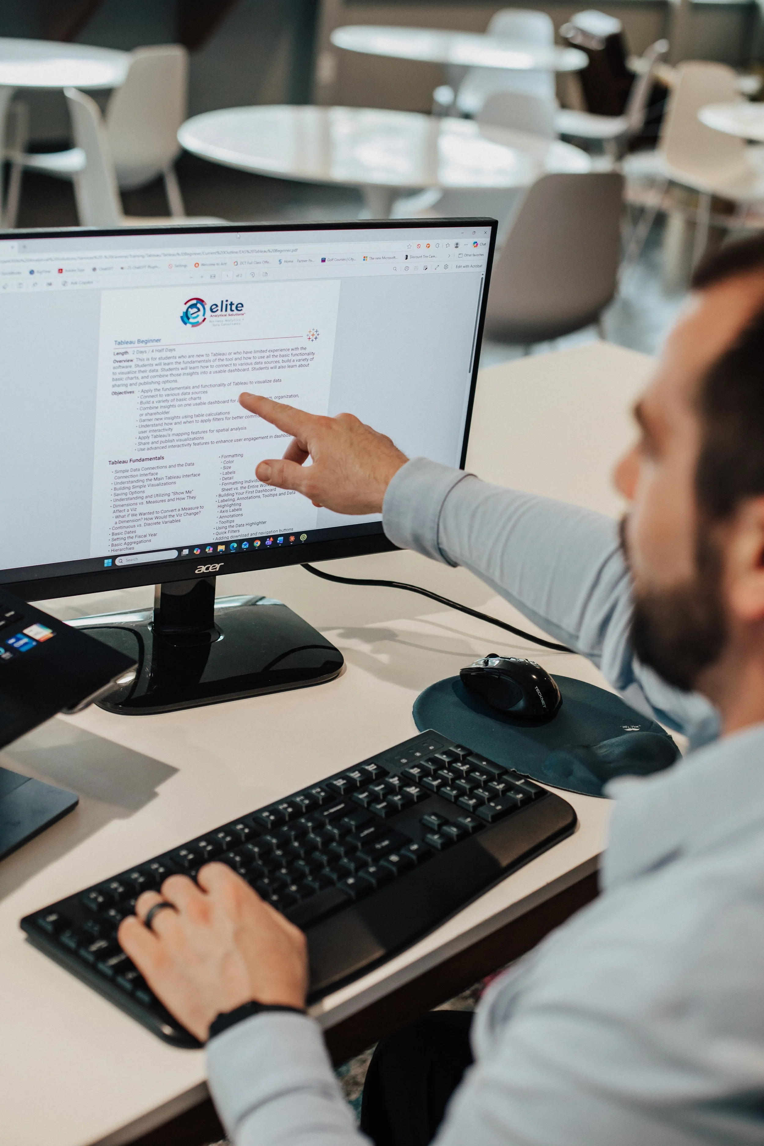 Person using a computer with a monitor displaying a webpage about Tableau beginner training course.