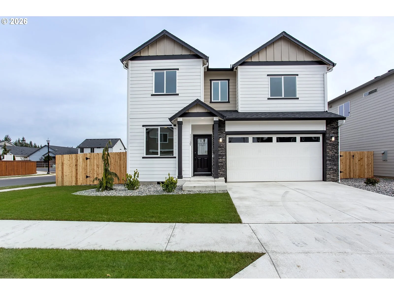 Photo of white two story home with a patch of grass and a fence behind the grass