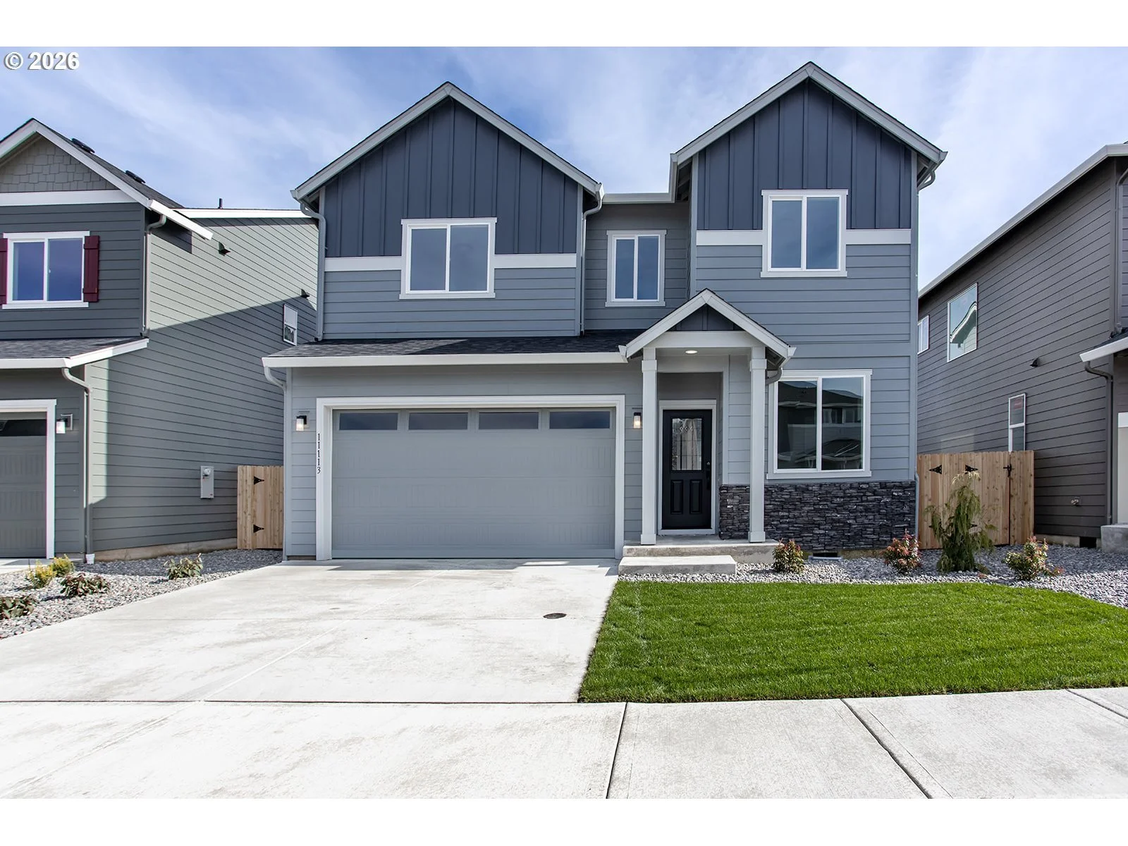 Photo of blue house with green grass on the left side of the.