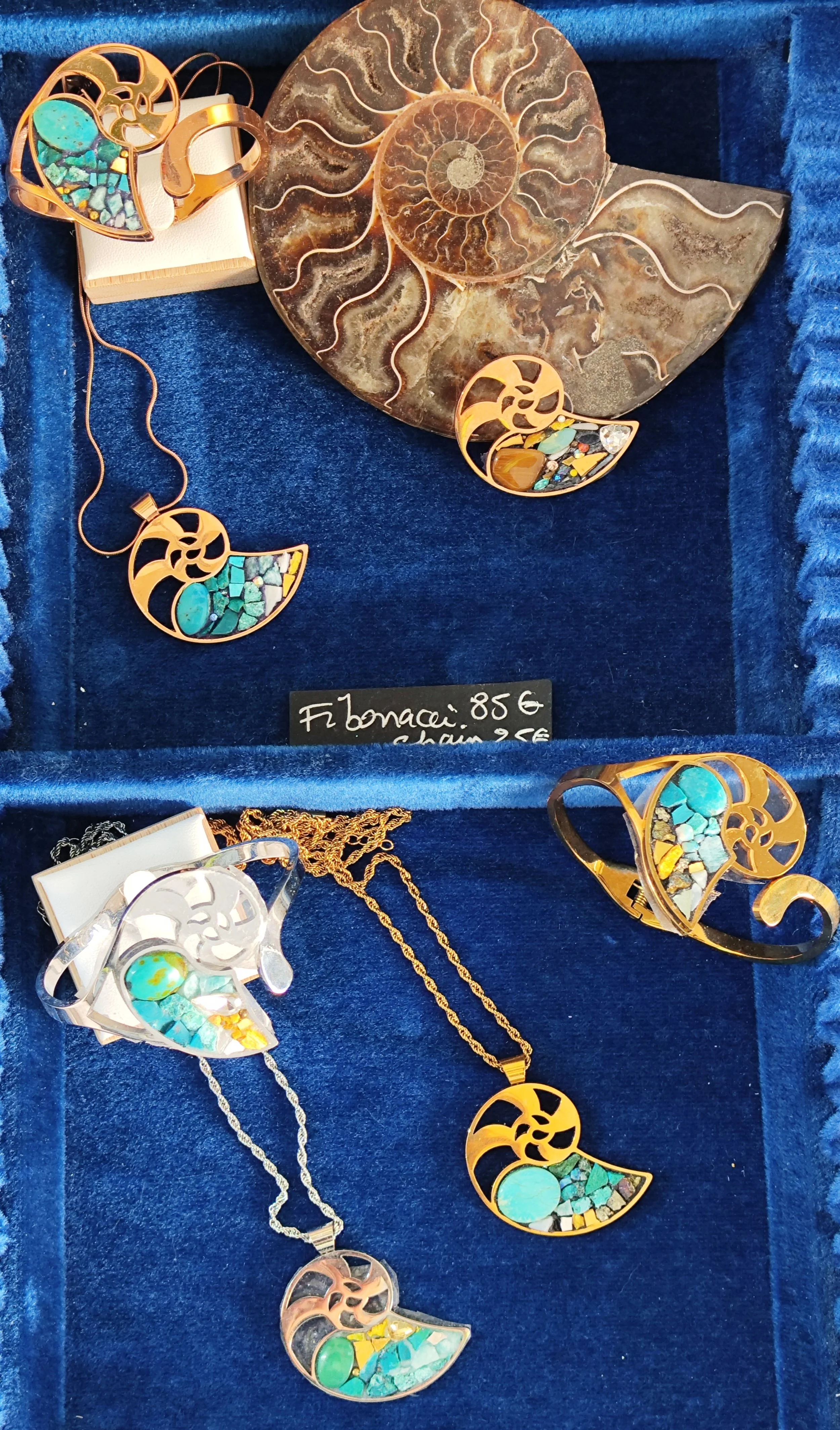 Bijoux en or avec pierres turquoise et autres pierres colorées, présentés dans une boîte en velours bleu