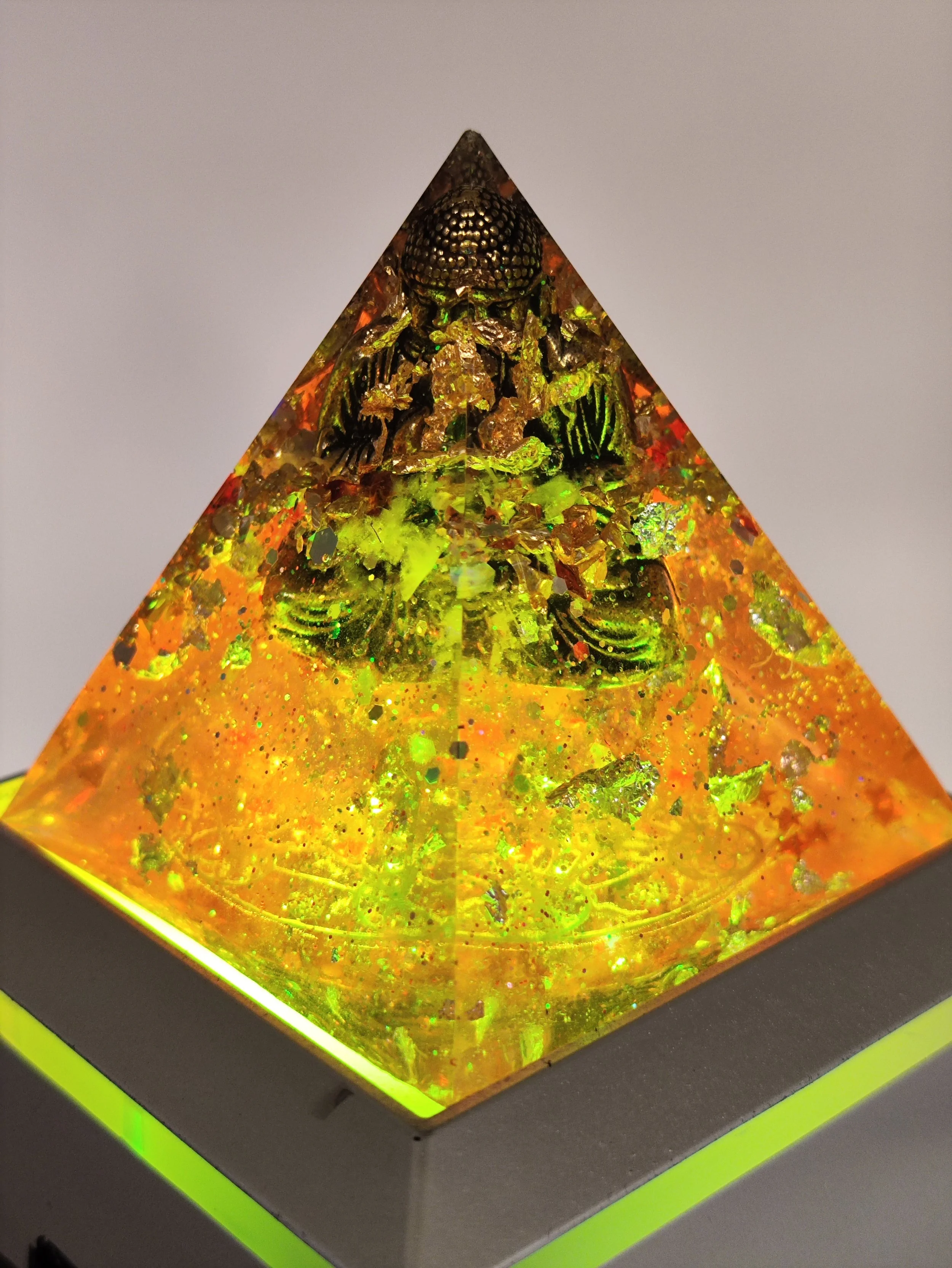 Orgonite pyramide sur lumieres de couleurs et blanche