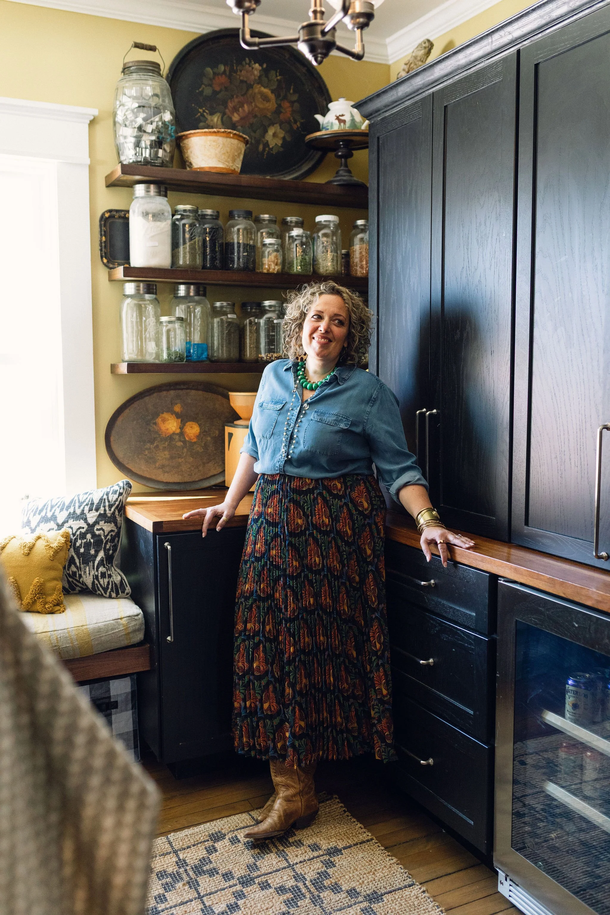 Virginia Patnode Macfawn standing in her pantry, surrounded by black custom-cabinetry, antiques, and glass jars.