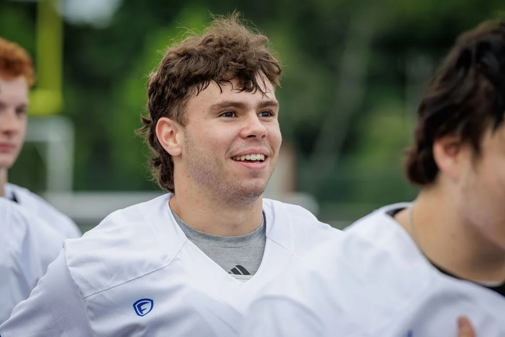 Young man in football uniform smiling during practice outdoors.