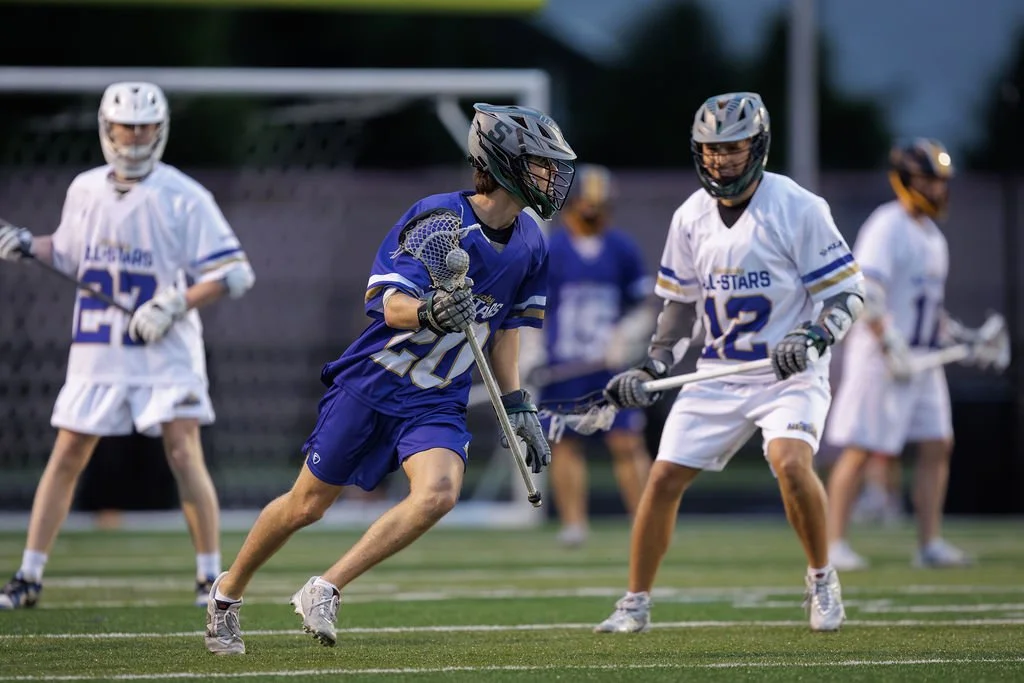 Lacrosse players in helmets and jerseys competing on a field during a game
