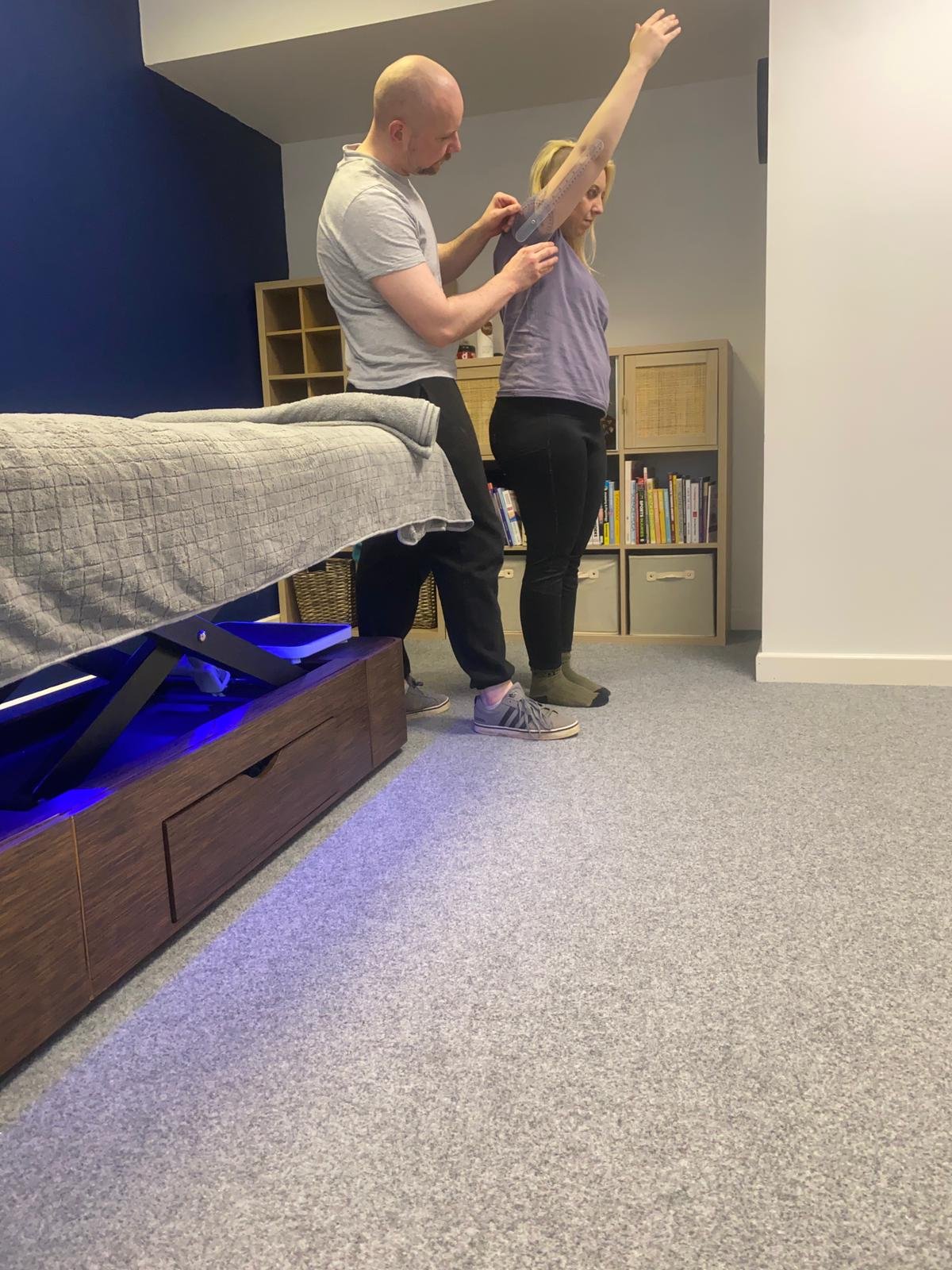 male msk therapist conducting an assessment of females shoulder mobility and movement within a clinic