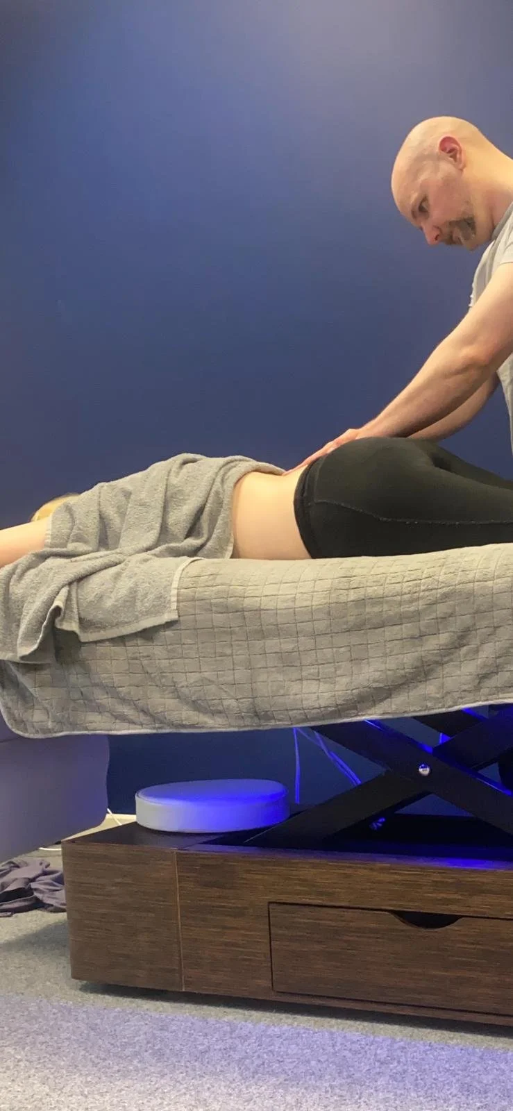 image of male sports massage therapist performing clinical massage on injured females lower back