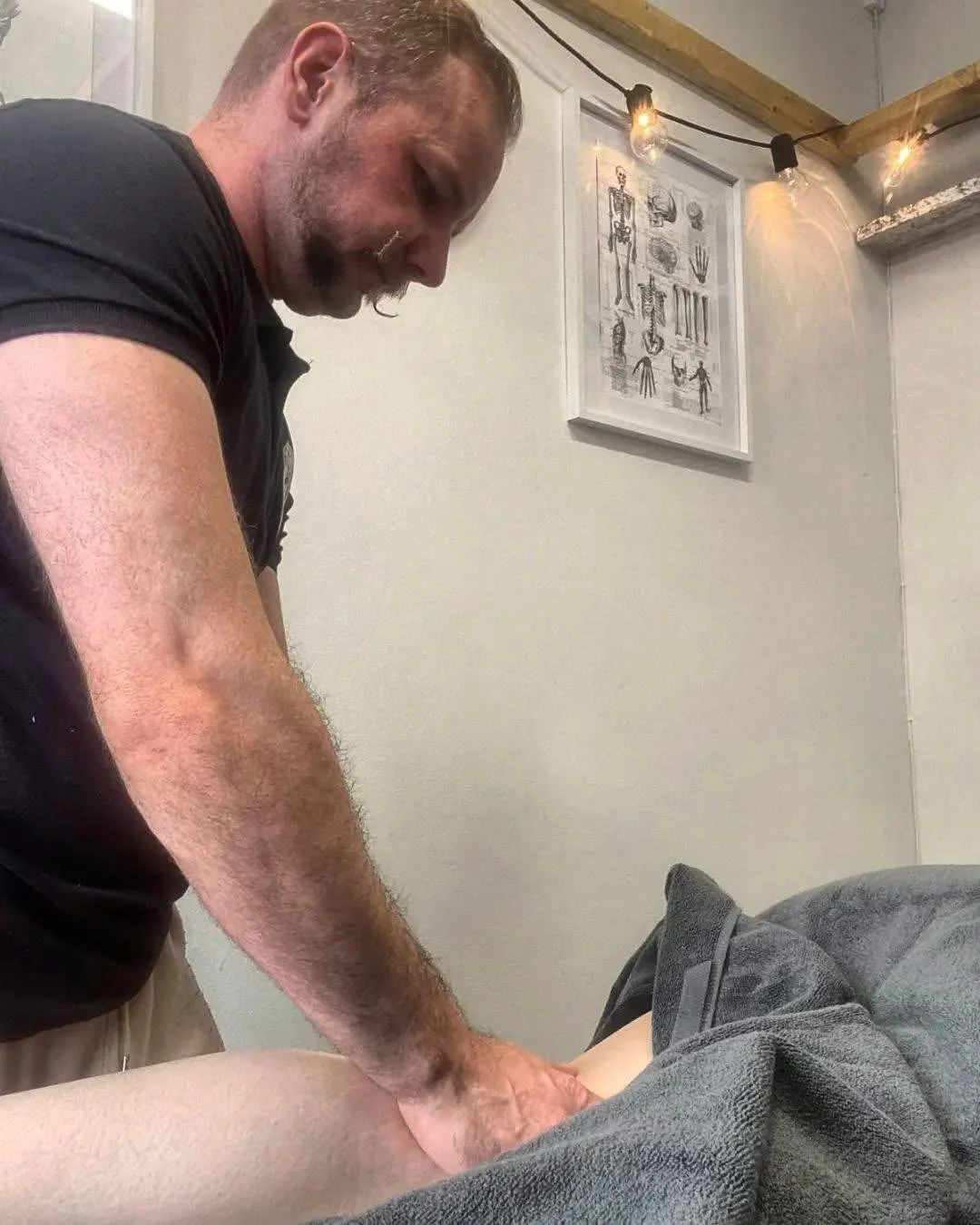 male msk therapist treating females leg with sports massage