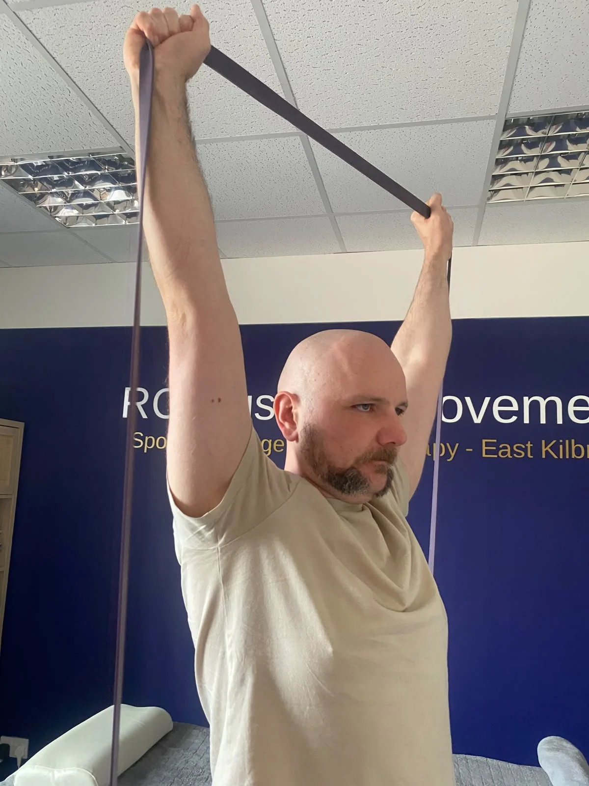 Ross using a resistance band to perform and overhead strengthening exercise