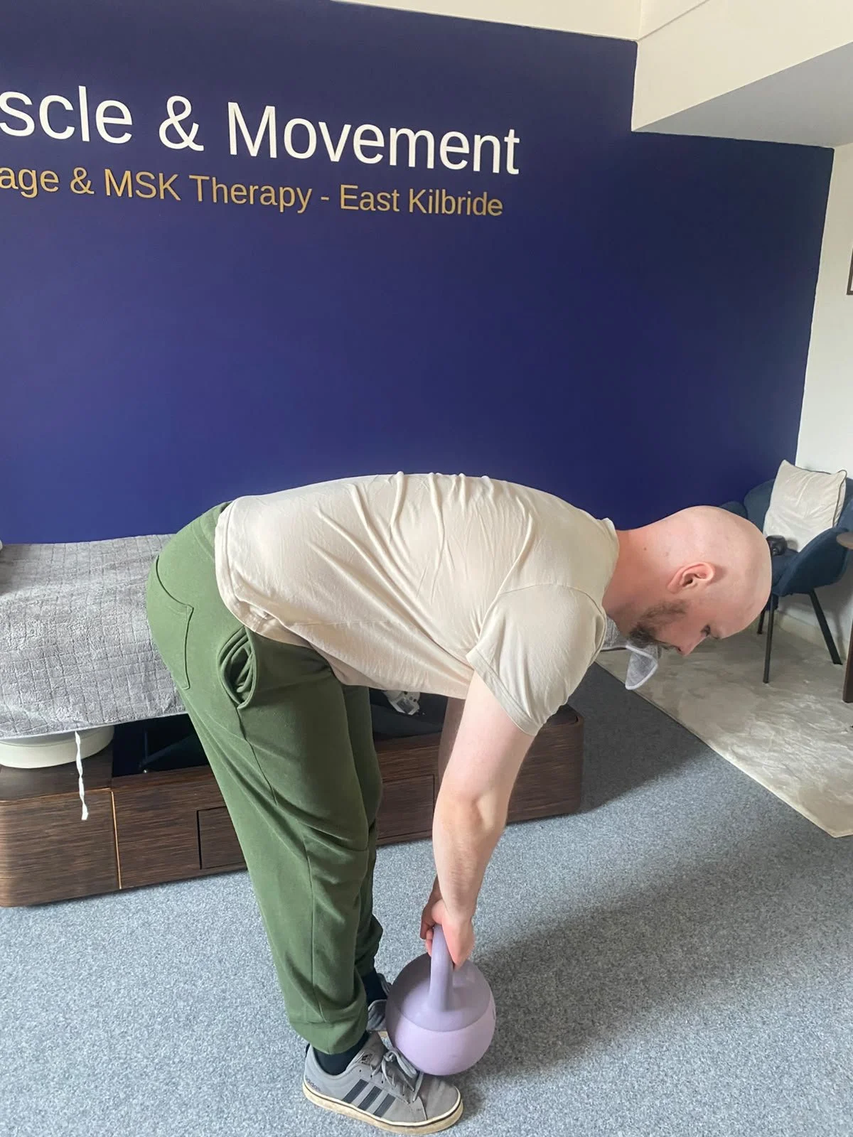 sports therapist showing the eccentric part of kettlebell deadlift