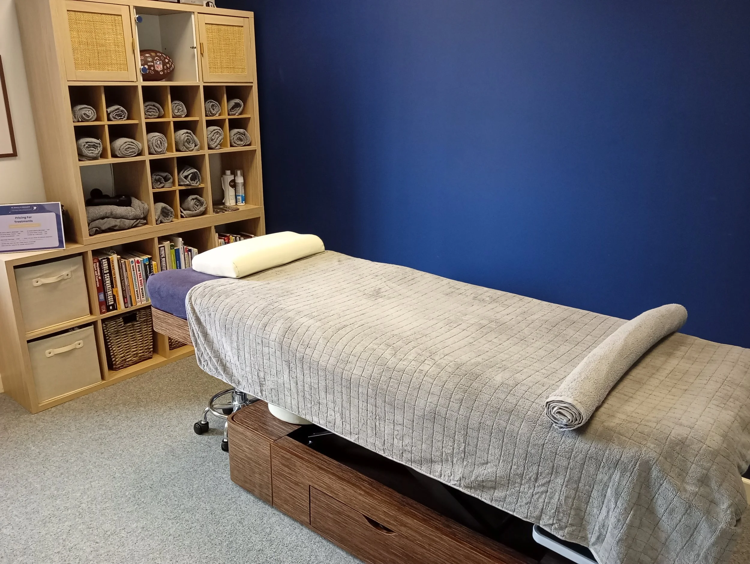 image at front angle of rcmm clinic showing massage plinth and towels on rack in the frame