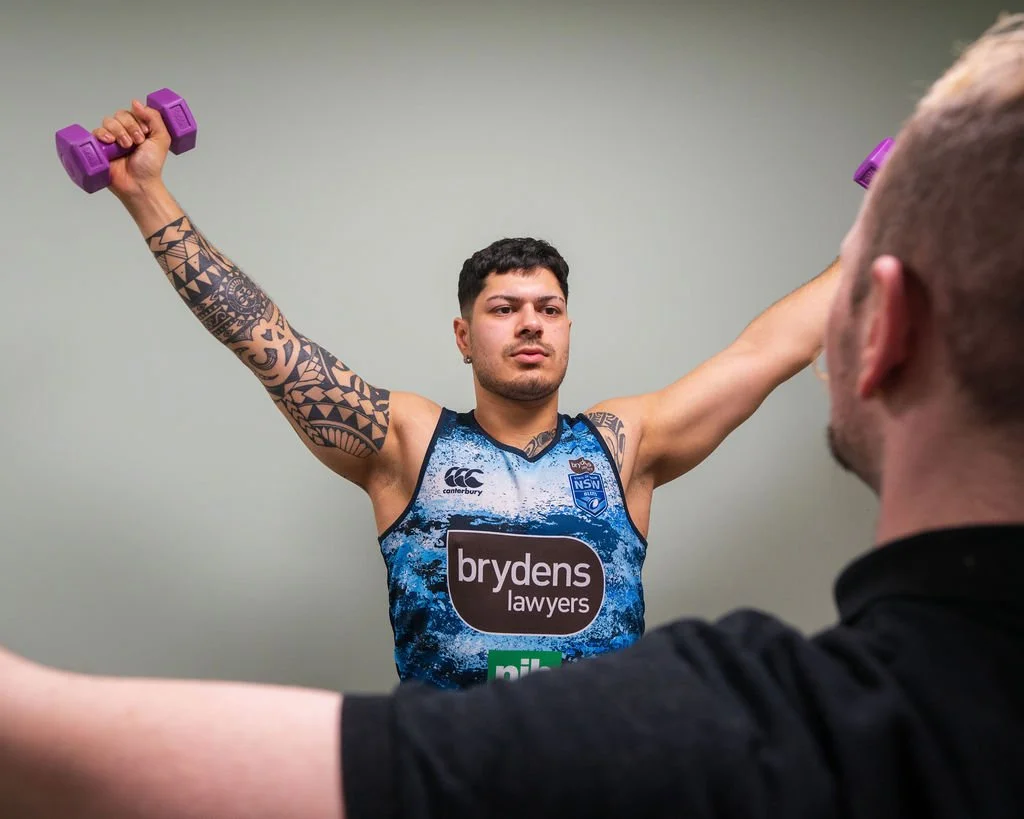 Ross testing shoulder mobility of client using Y raises and dumbells