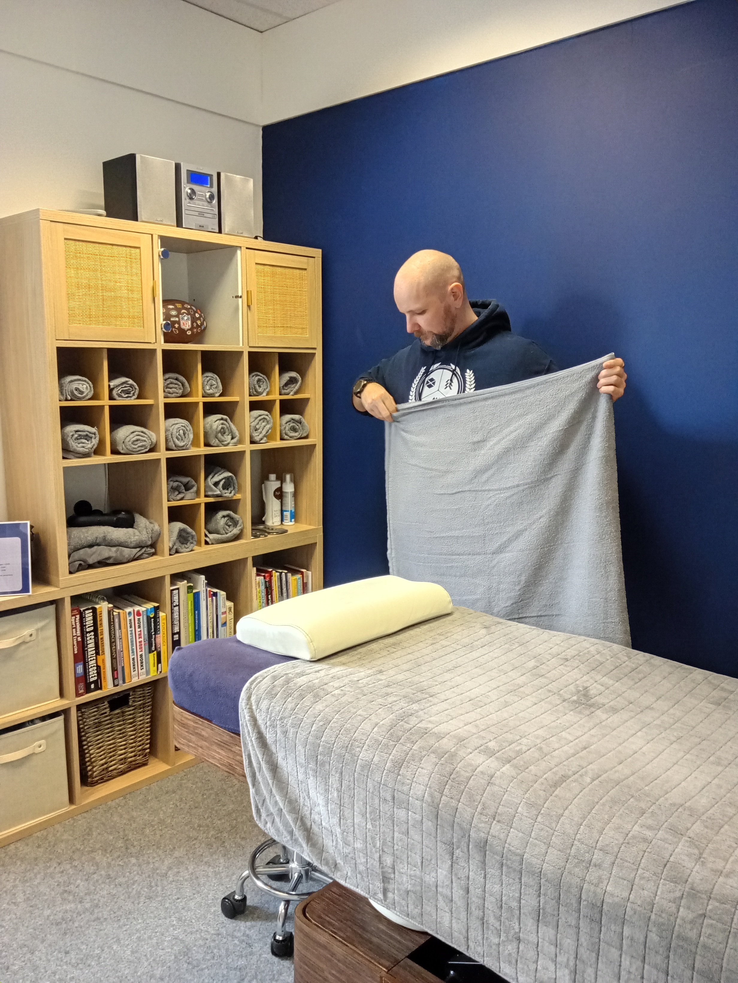 image of sports therapist Ross folding towels , keeping clinic clean and tidy
