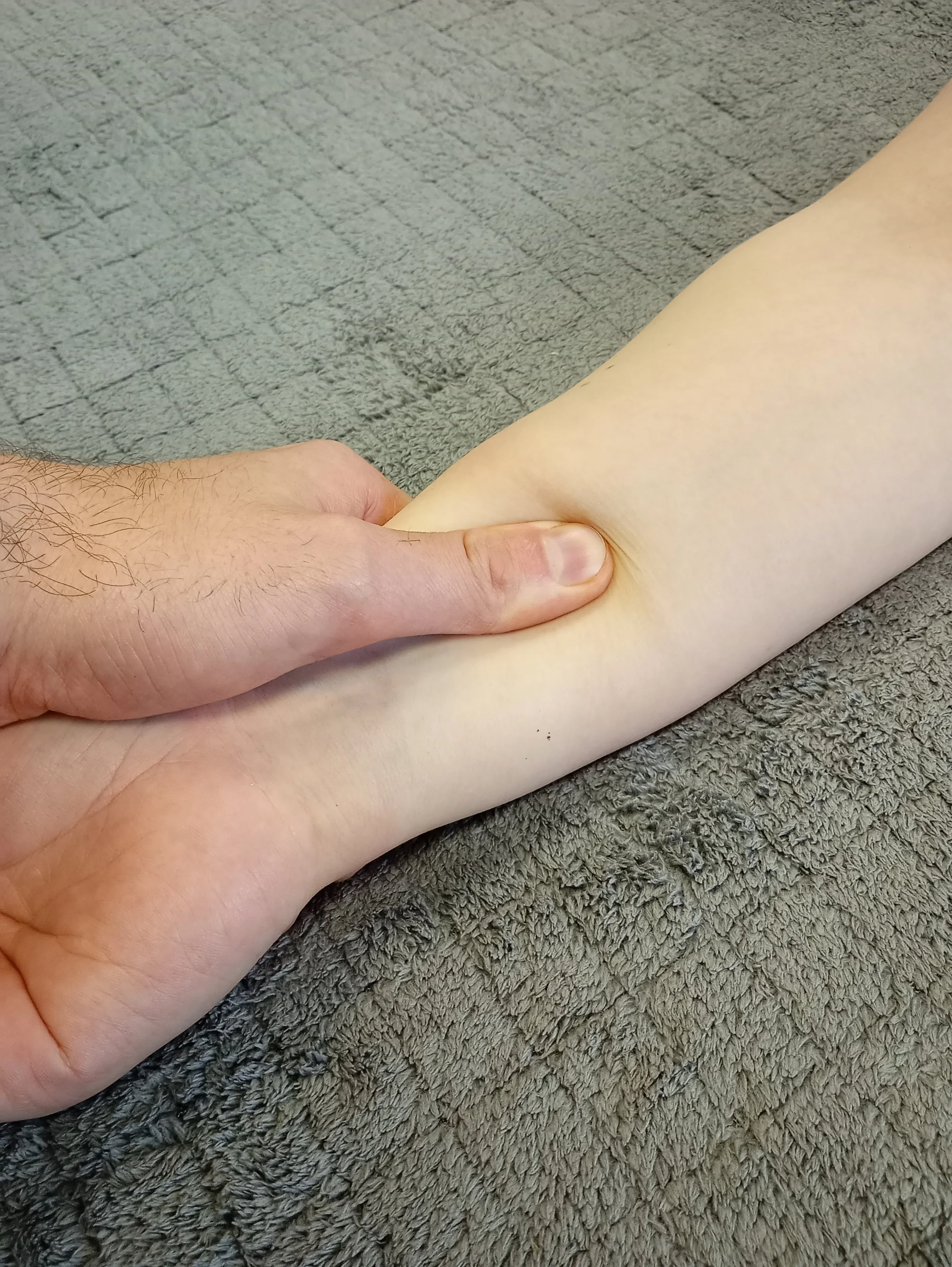 Controlled massage pressure applied to a client’s arm, illustrating how hands-on contact provides sensory input during treatment.