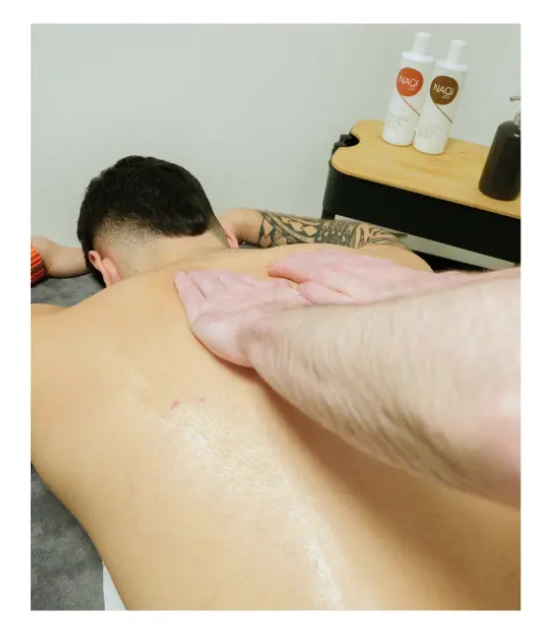 image of sports massage therapist performing sports massage on upper back of male client