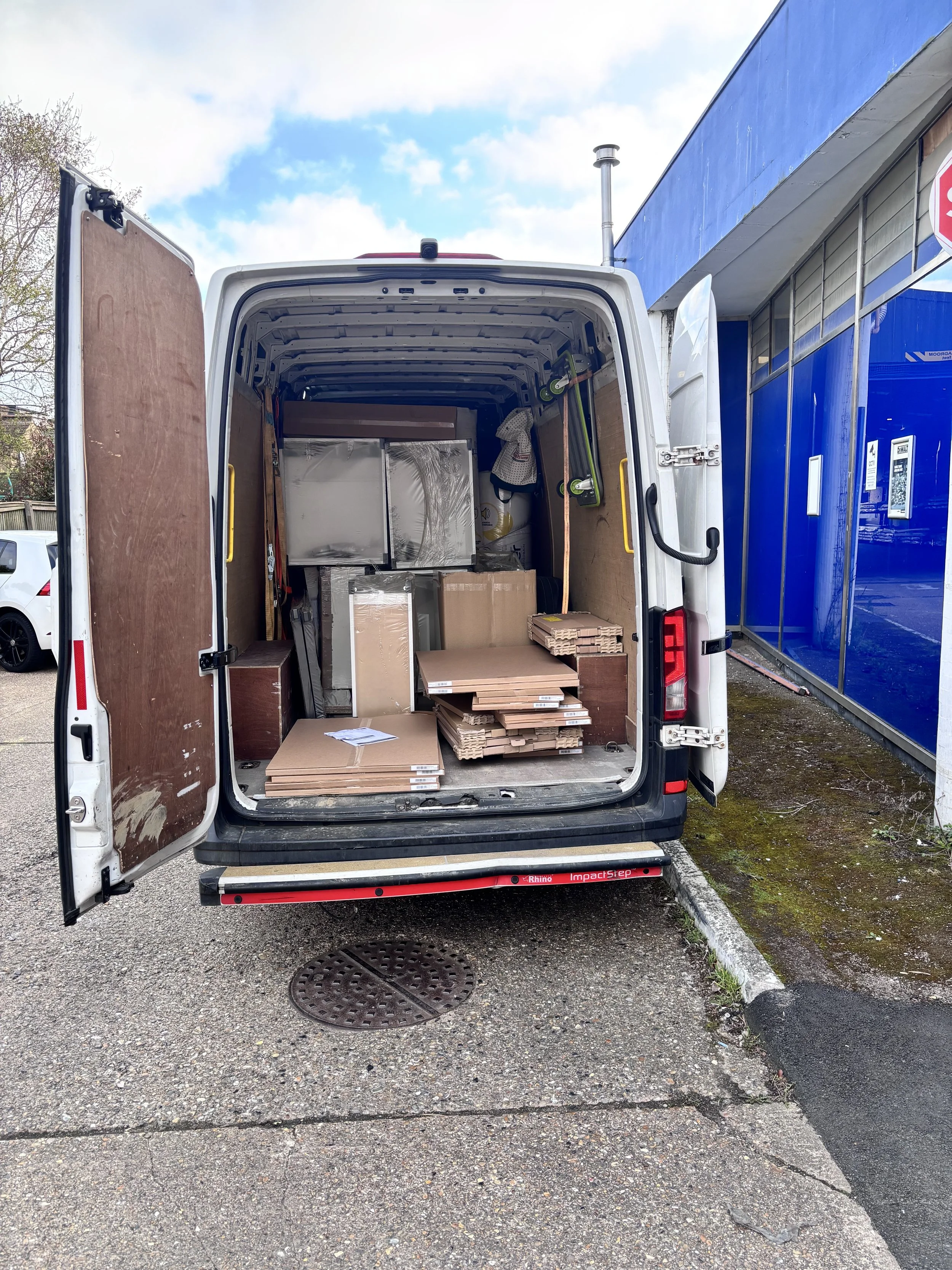 Open van with loaded boxes, furniture, and boxes inside parked in a parking lot.