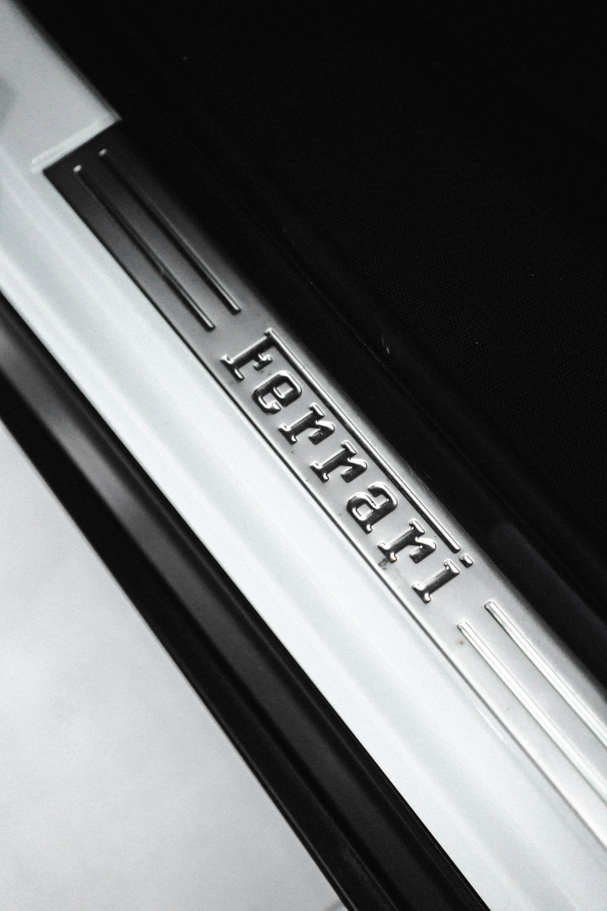 Close-up of a metallic door sill plate with the word 'Lamborghini' engraved on it.
