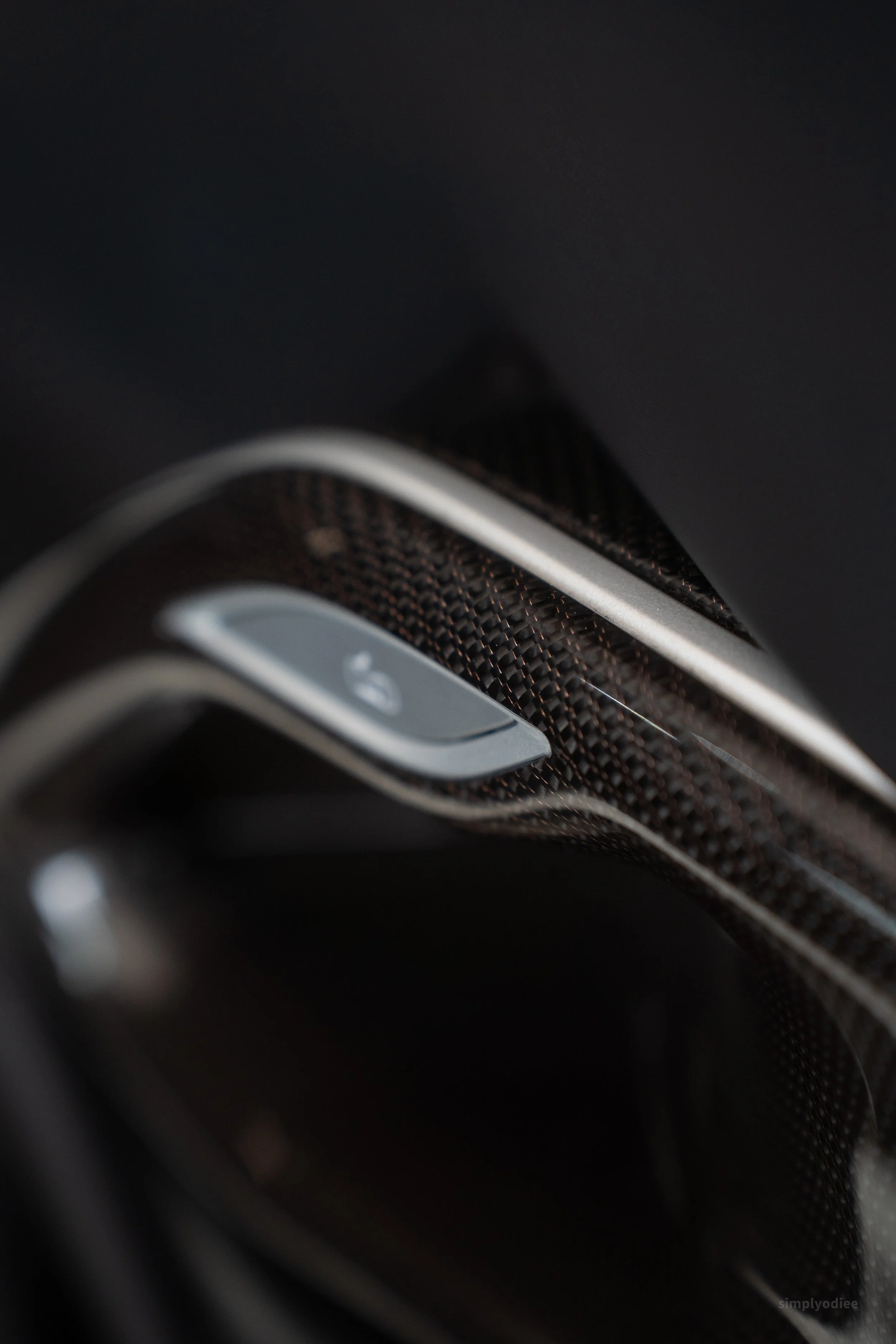 A close-up view of a black and silver car key fob with a lock icon, resting on a dark surface.
