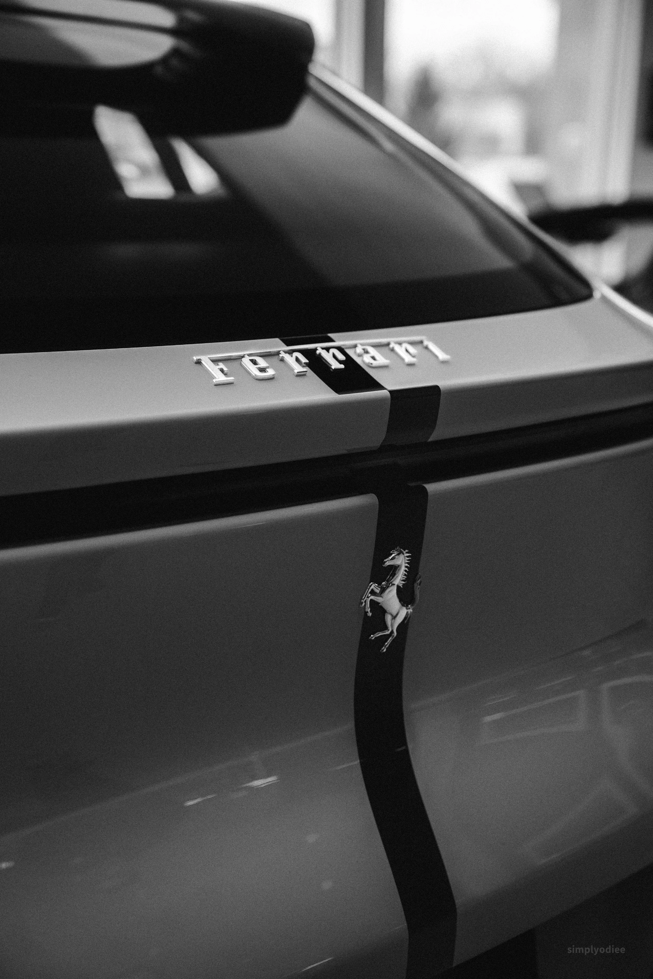 Close-up of a black and white Ferrari car with a visible Ferrari logo and a distinctive stripe design.