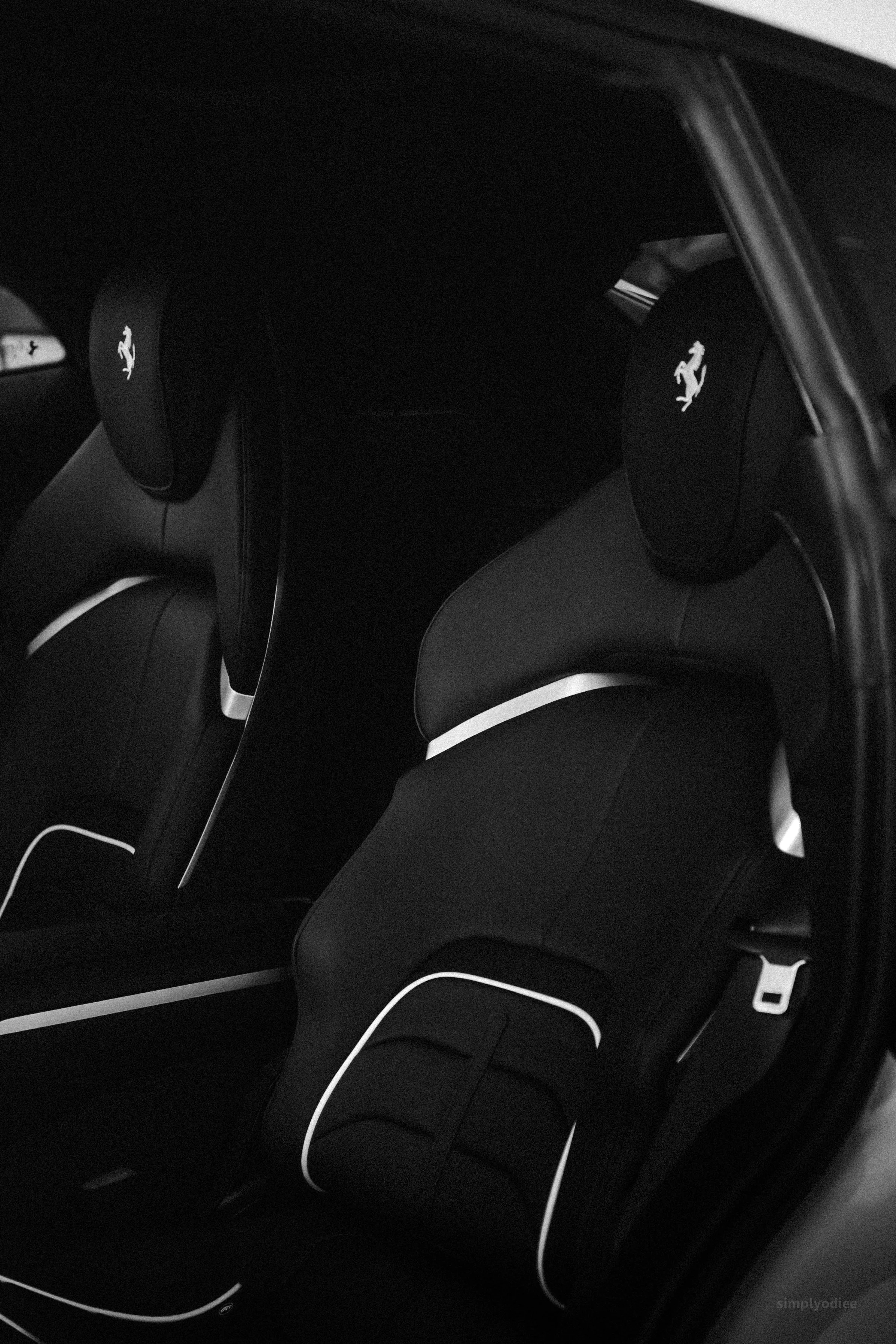 Black car interior with headrests featuring the Ferrari logo and white accent lines.