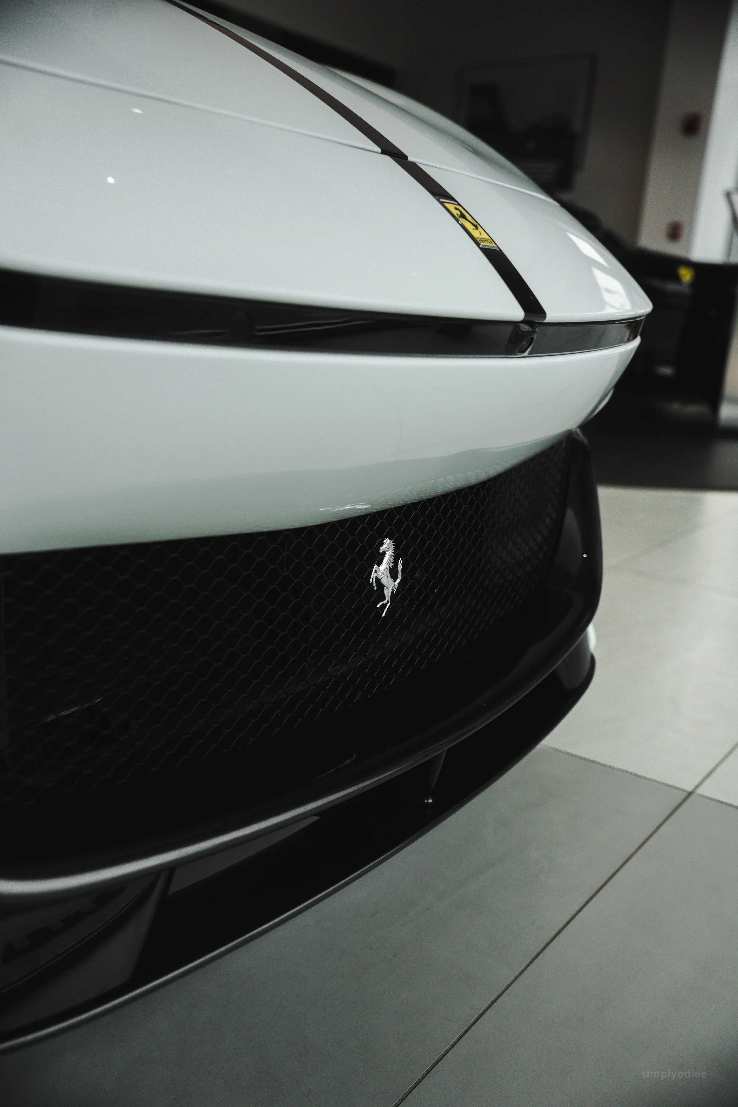 Close-up of a white Ferrari sports car's front, showing the emblem and black grille.