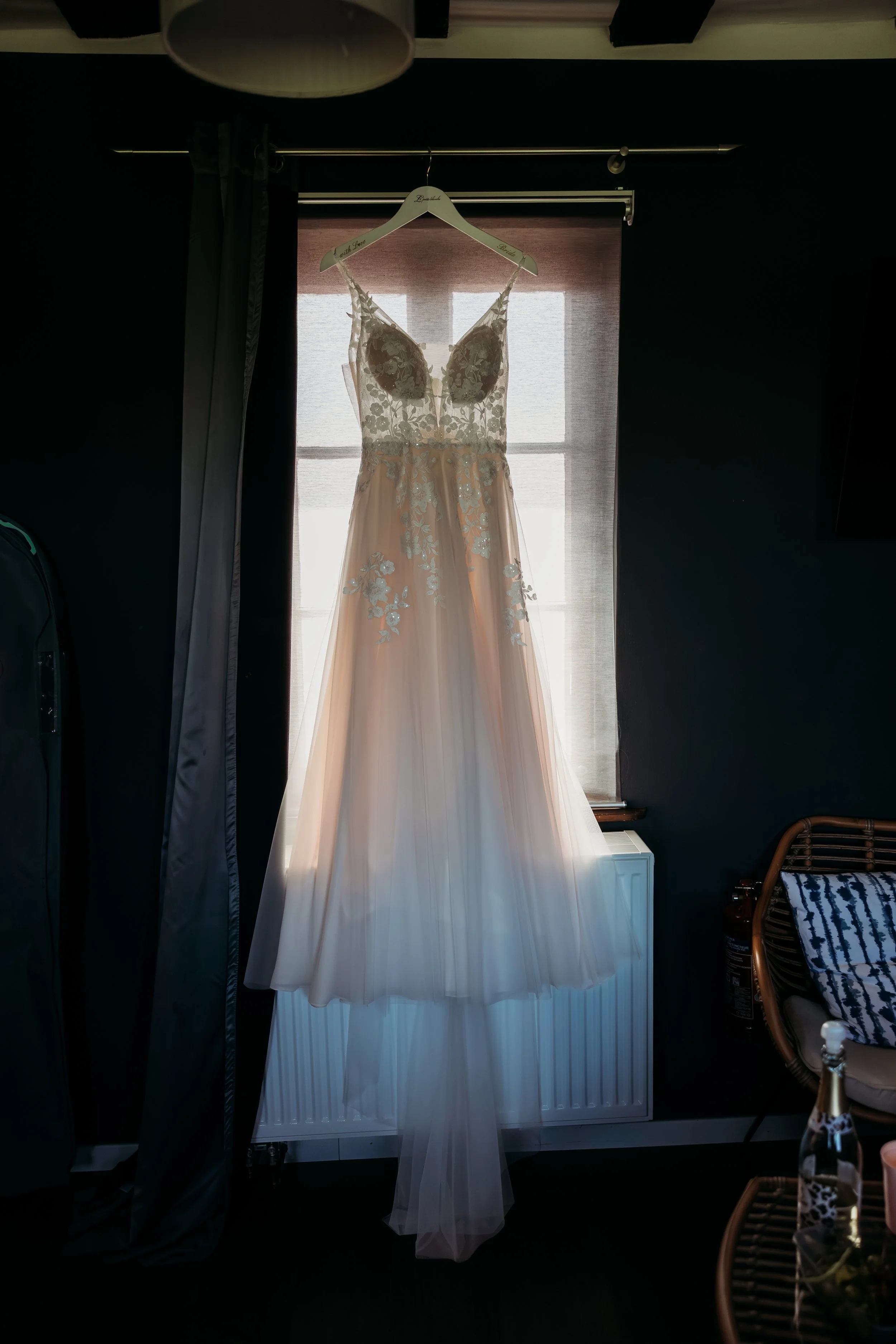 Ein Hochzeitskleid hängt vor einem Fenster auf einer Garderobe auf Mathis Wiesenmühle