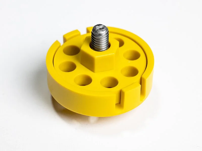 A yellow plastic adjustable reloading press shell holder with a metal screw in the center
