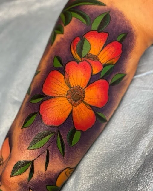 A colorful tattoo of three orange and red flowers with green leaves on a person's arm, with a purple background.