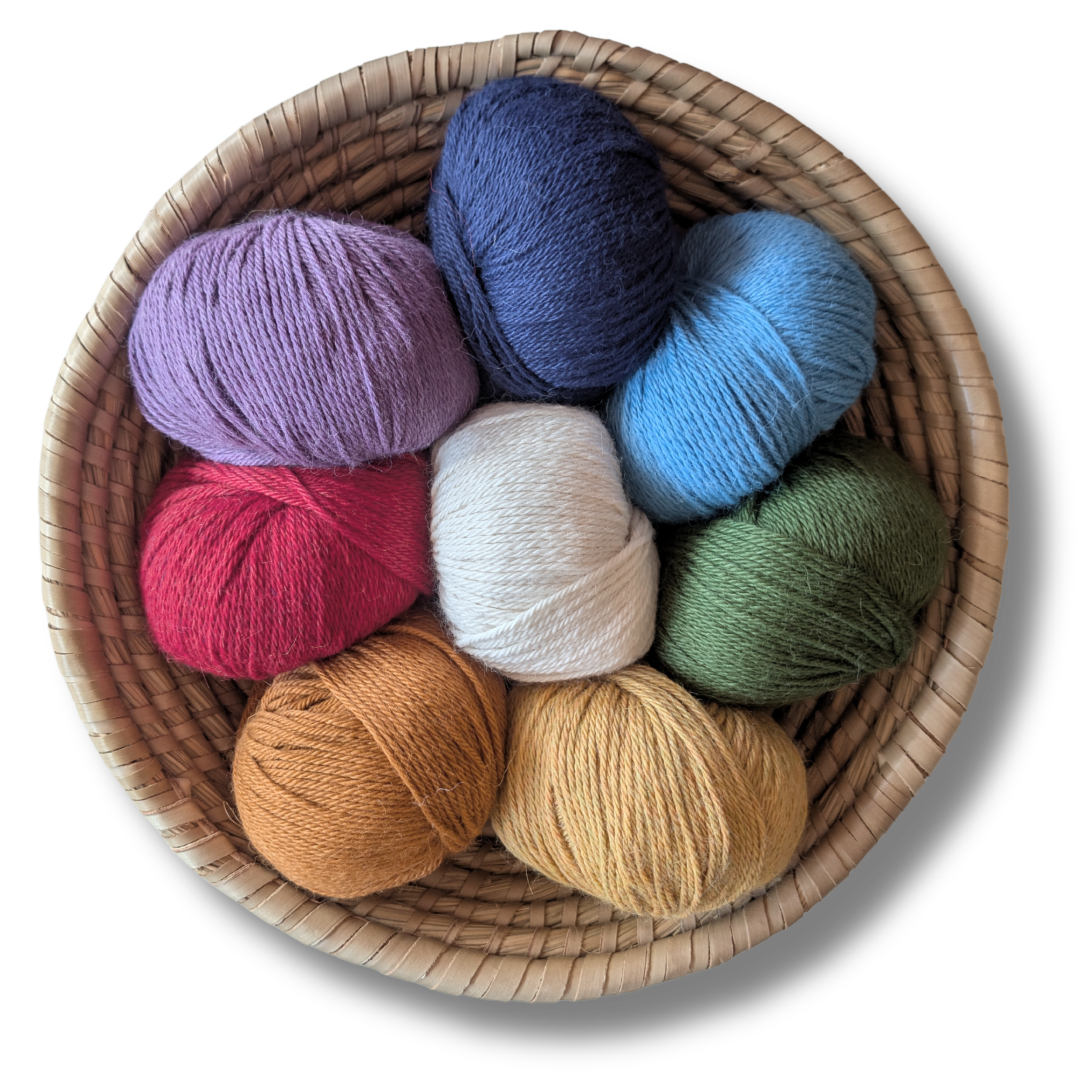 Blick in einen Korb voller bunter Wollknäuel, die in verschiedenen Farben wie Lila, Blau, Rot, Creme, Grün, Beige, Gelb, Orange und Braun gehalten sind.