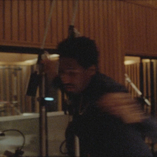 Jon Batiste, A person with dark hair and glasses in a recording studio, surrounded by soundproof panels and recording equipment.