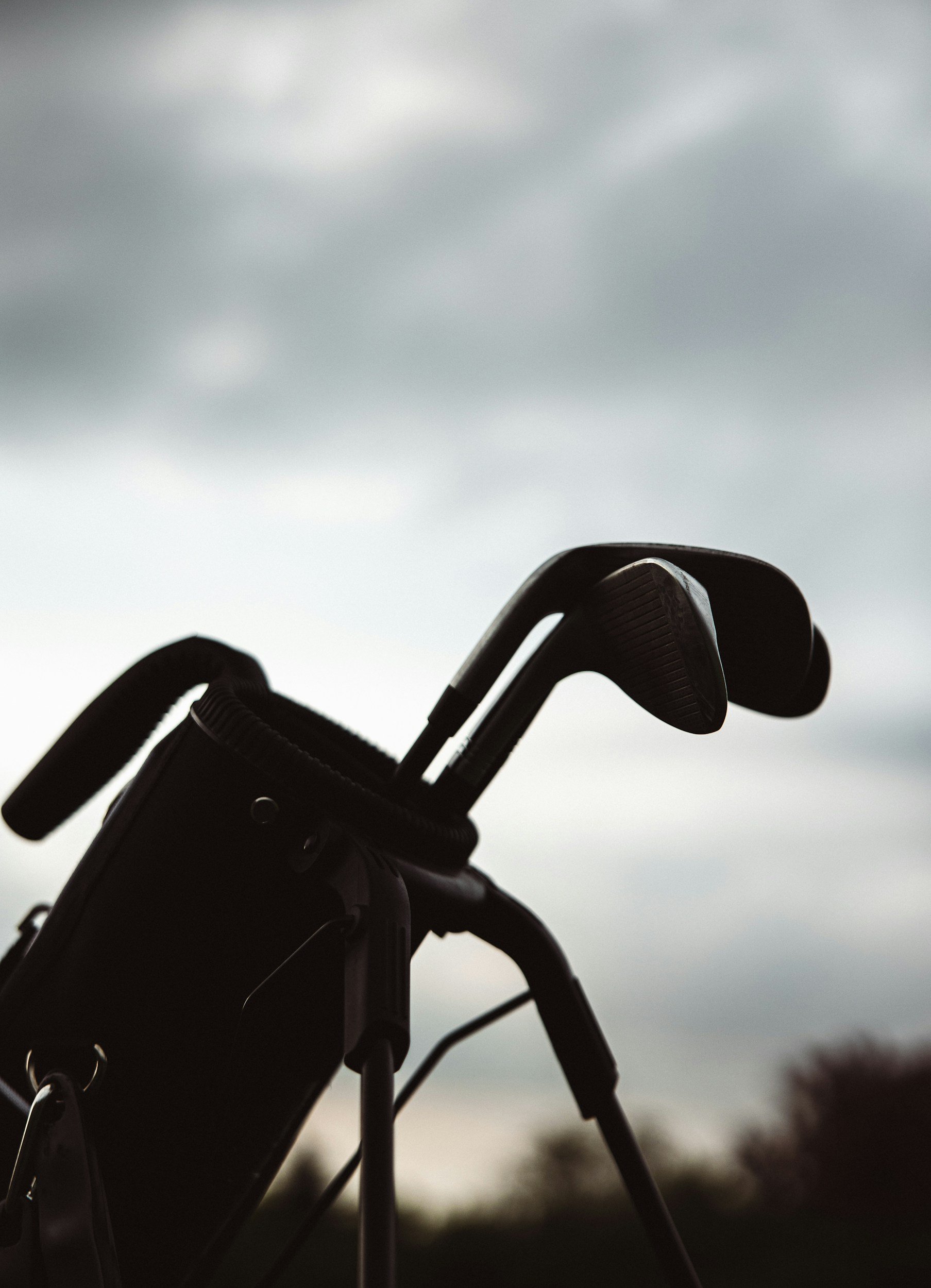 Close-up of golf clubs in a golf bag against an overcast sky.