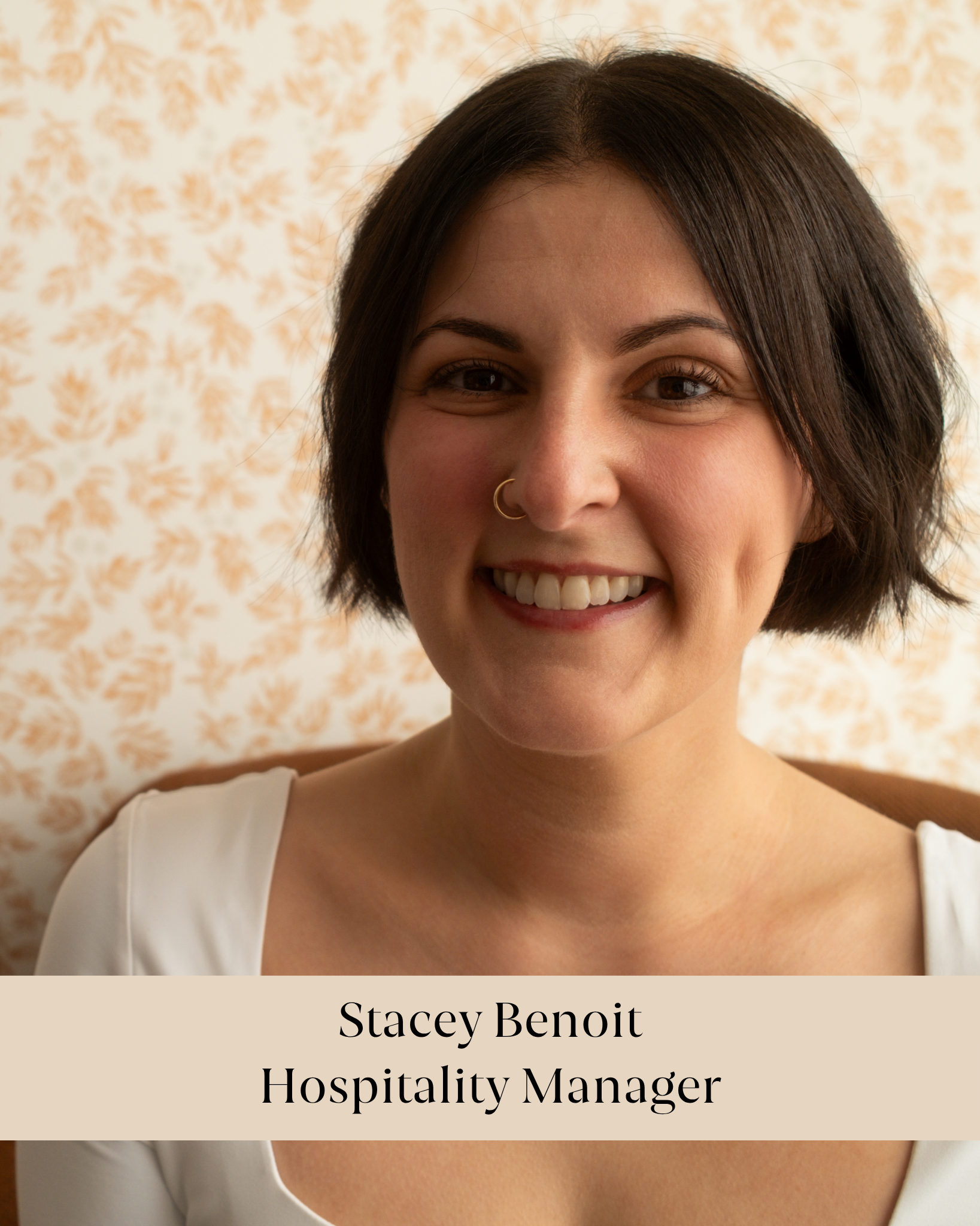 Close-up photograph of a woman with short dark hair, smiling, wearing a white top, with a cream-colored background featuring a floral pattern. The overlaid text reads: Stacey Benoit Hospitality Manager.