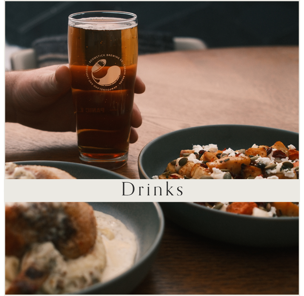 A person holding a pint glass of amber beer with a logo, and a plate of food with roasted vegetables, cheese, and nuts on a wooden table, with a subtitle "Drinks".