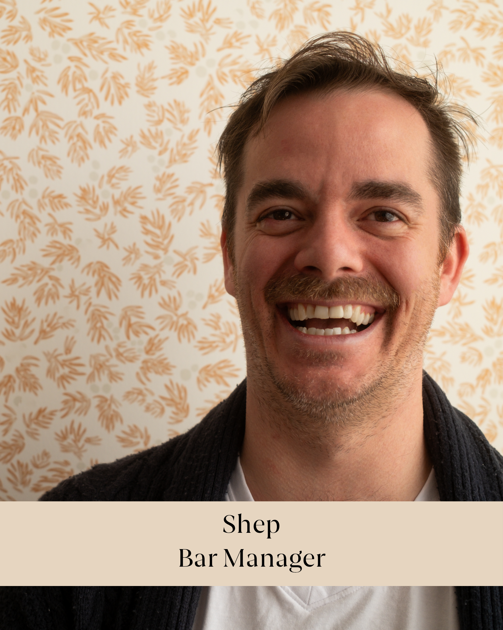 Close-up of a smiling man with a beard, wearing a black sweater and white shirt, against a beige background with an orange floral pattern. Text overlay reads: "Shep Bar Manager".